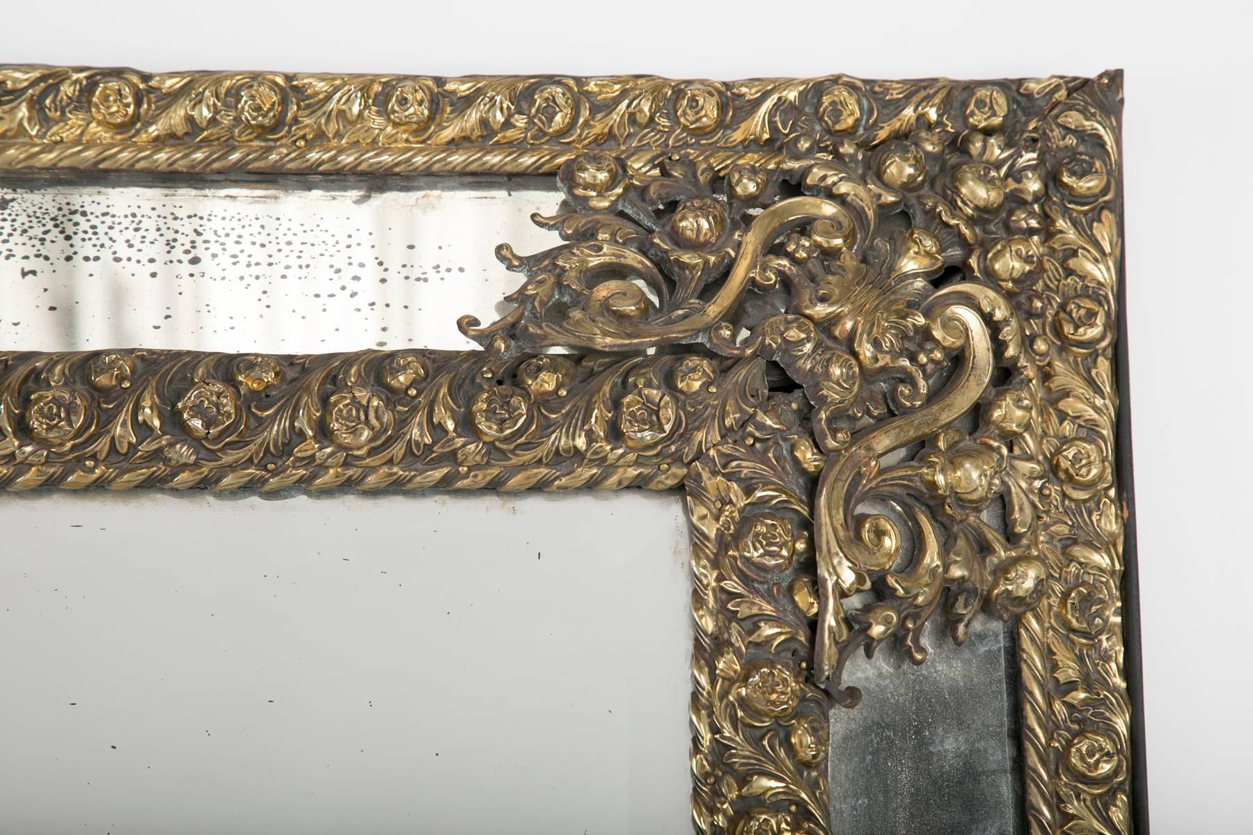 Dutch Baroque style pierced and hammered brass rectangular cushion mirror. The central mirror plate raised and surrounded by four decorative plates. 

Large Scale 59 by 36.5 by 3 inches.