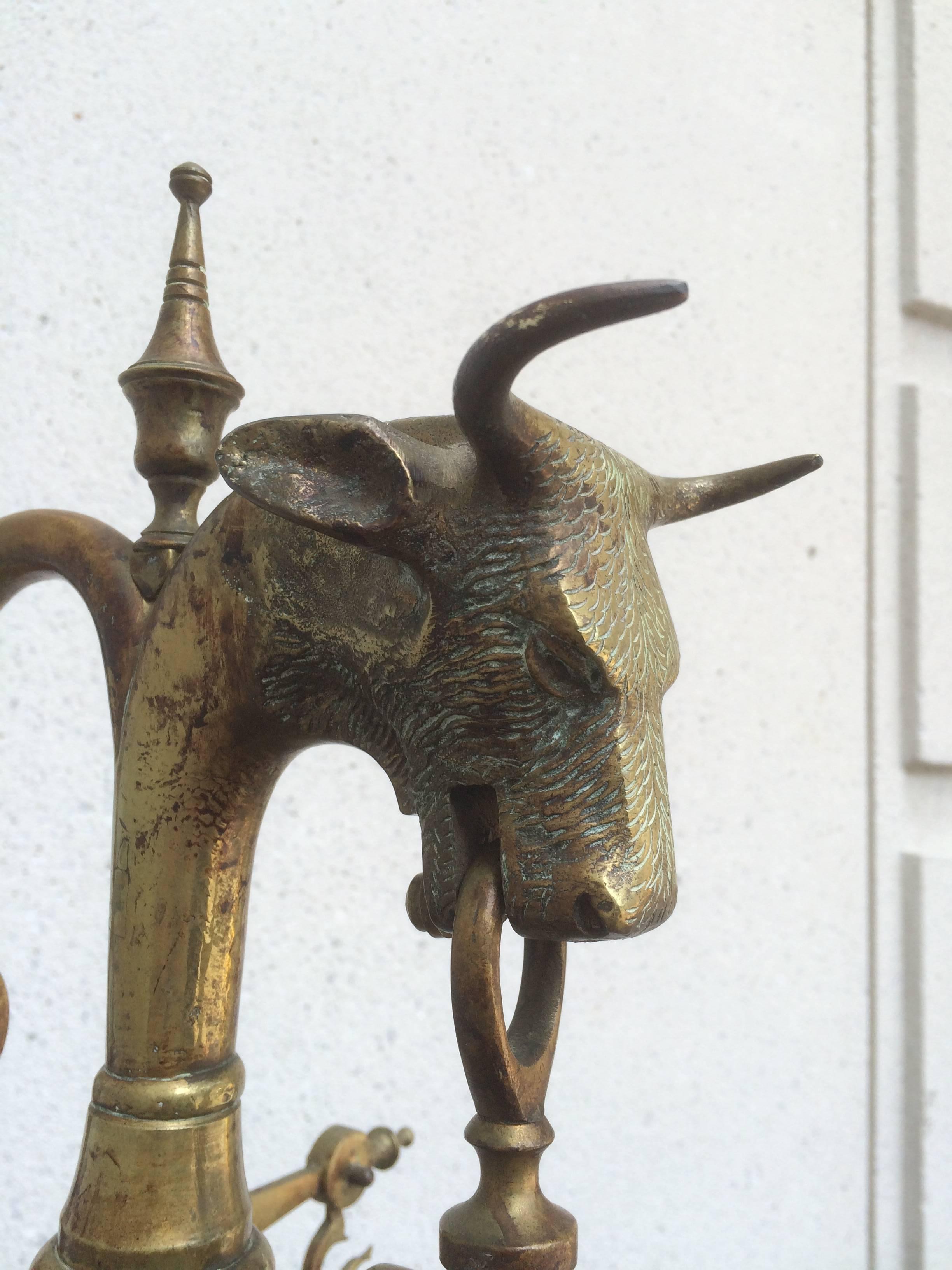 Impressive large brass balance beam scale with wonderful decorative bull's head on top and the hooks holding the scales in the form of dolphins. With original weights set into the base. 
Over five feet tall!