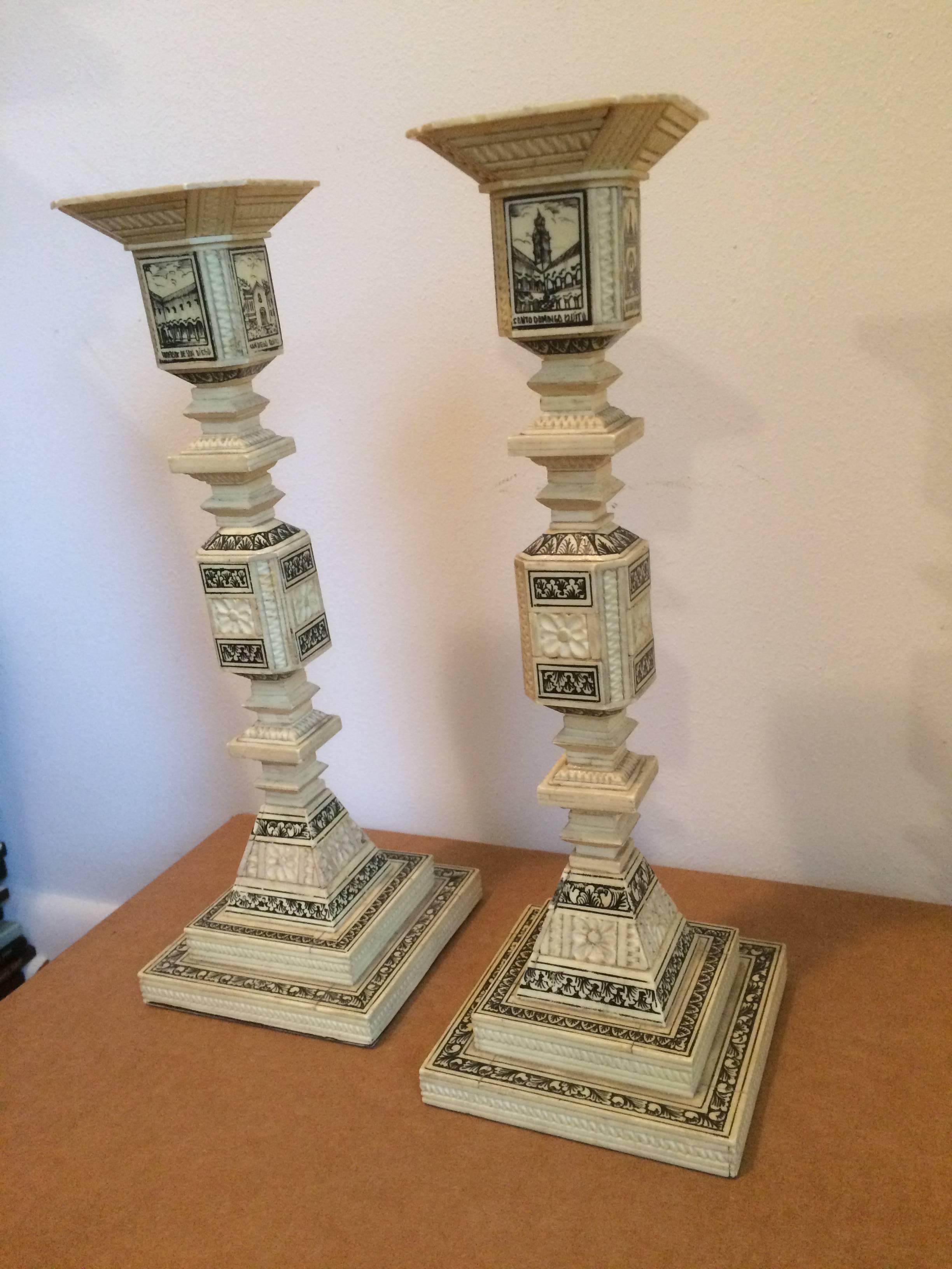 Pair of carved and inked Ecuadoran llama bone candlesticks, in an appealing geometric form, with inked decoration. Each candlestick depicting four architectural treasures of Quito, Ecuador, including various churches, including San Diego, La