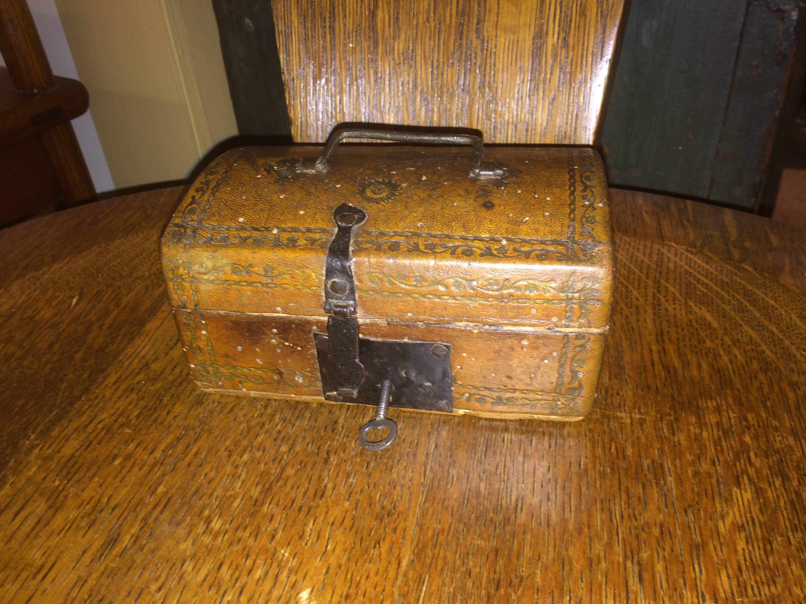 An all original French tooled and gilt leather box with wrought iron handle, hasp and lock plate. Lined with early manuscript leaves. 