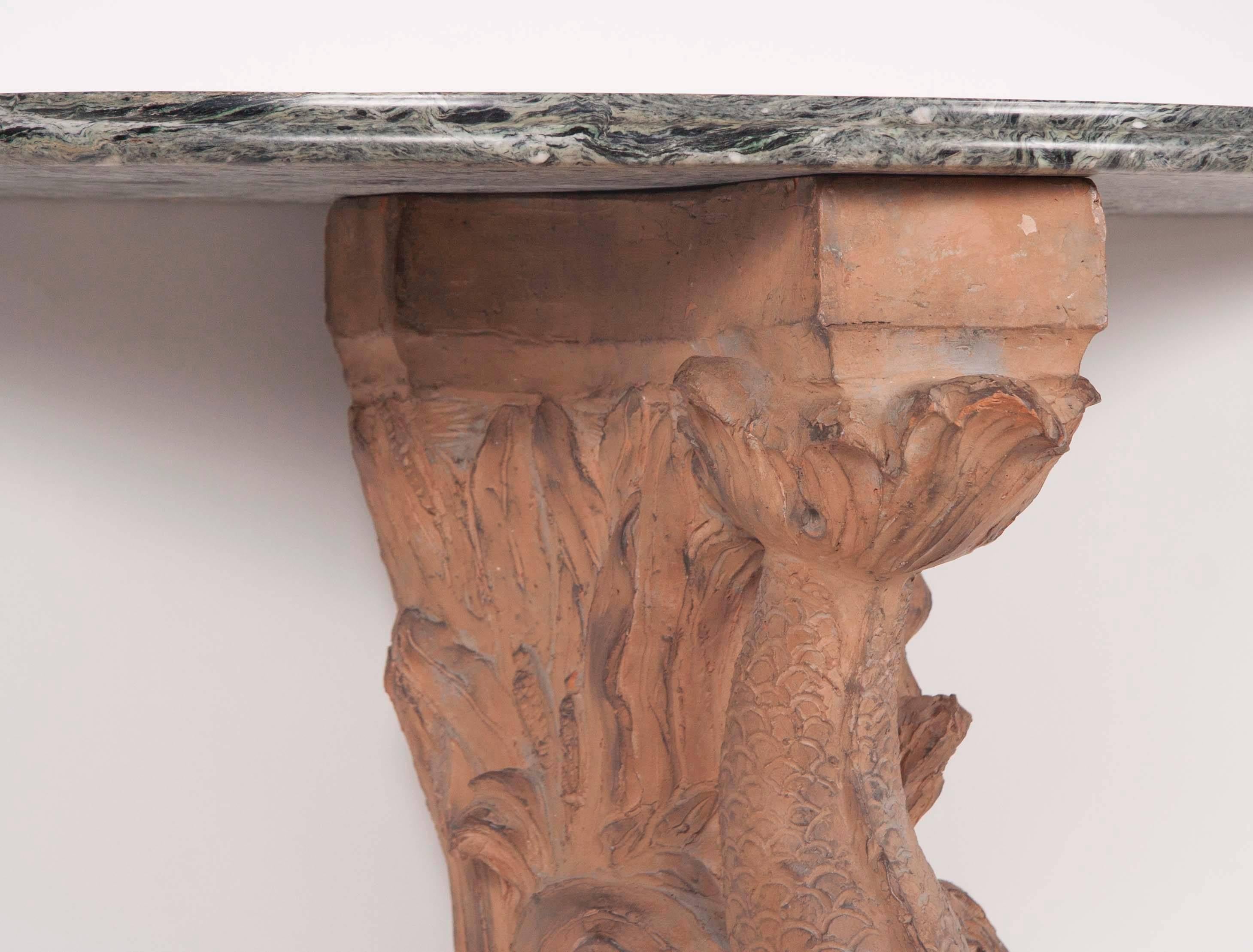 Impressive pair of console tables with terracotta supports in the form of dolphins with shaped green marble tops and bases. Italian, circa 1900.