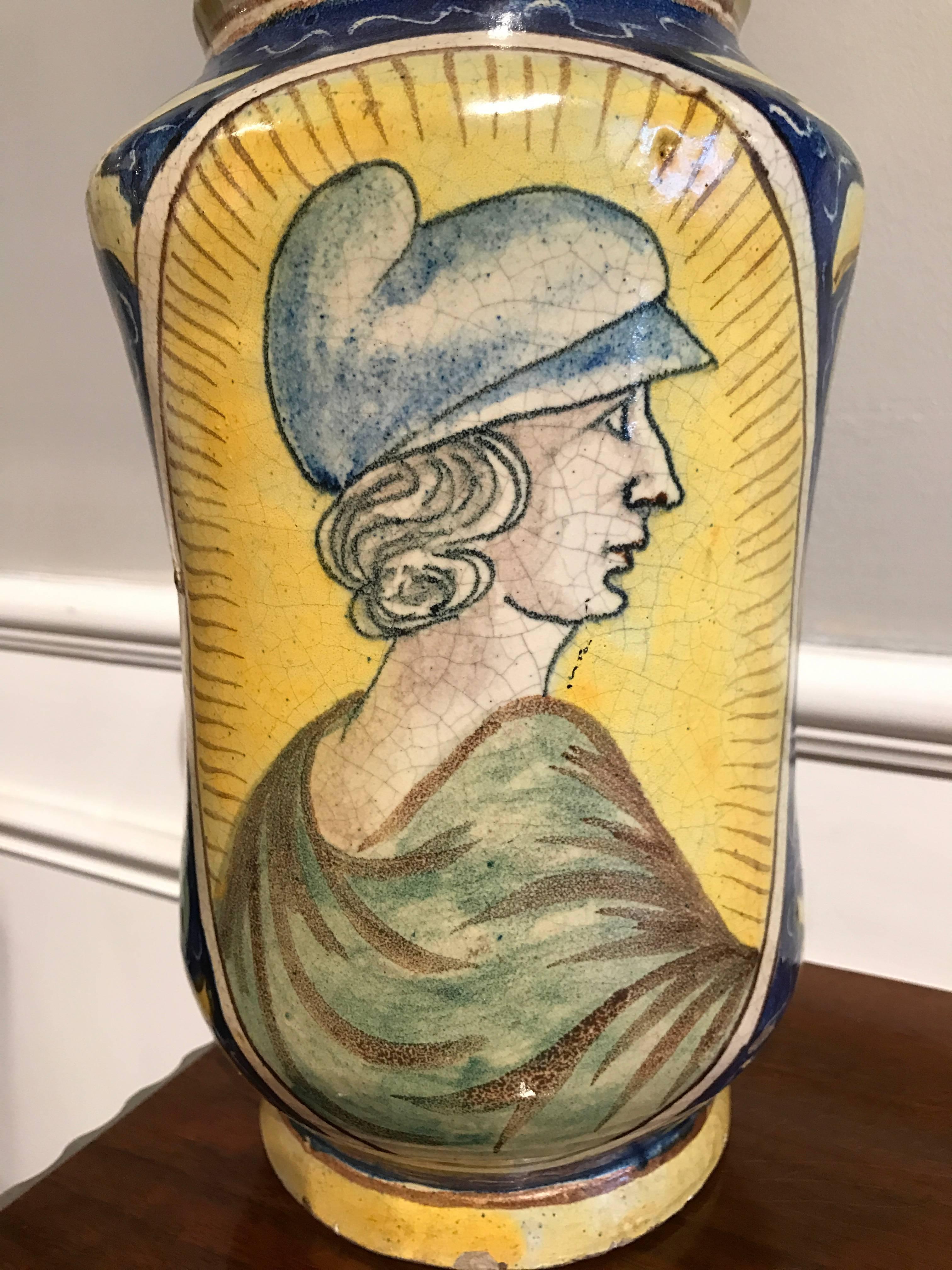 An impressive 17th century polychrome decorated drug jar or 'Albarello'.

The Albarello is of a typical waisted shape, and is decorated profusely in polychrome with a wonderful portrait of a man wearing a 'Dantesque' cap contained within an