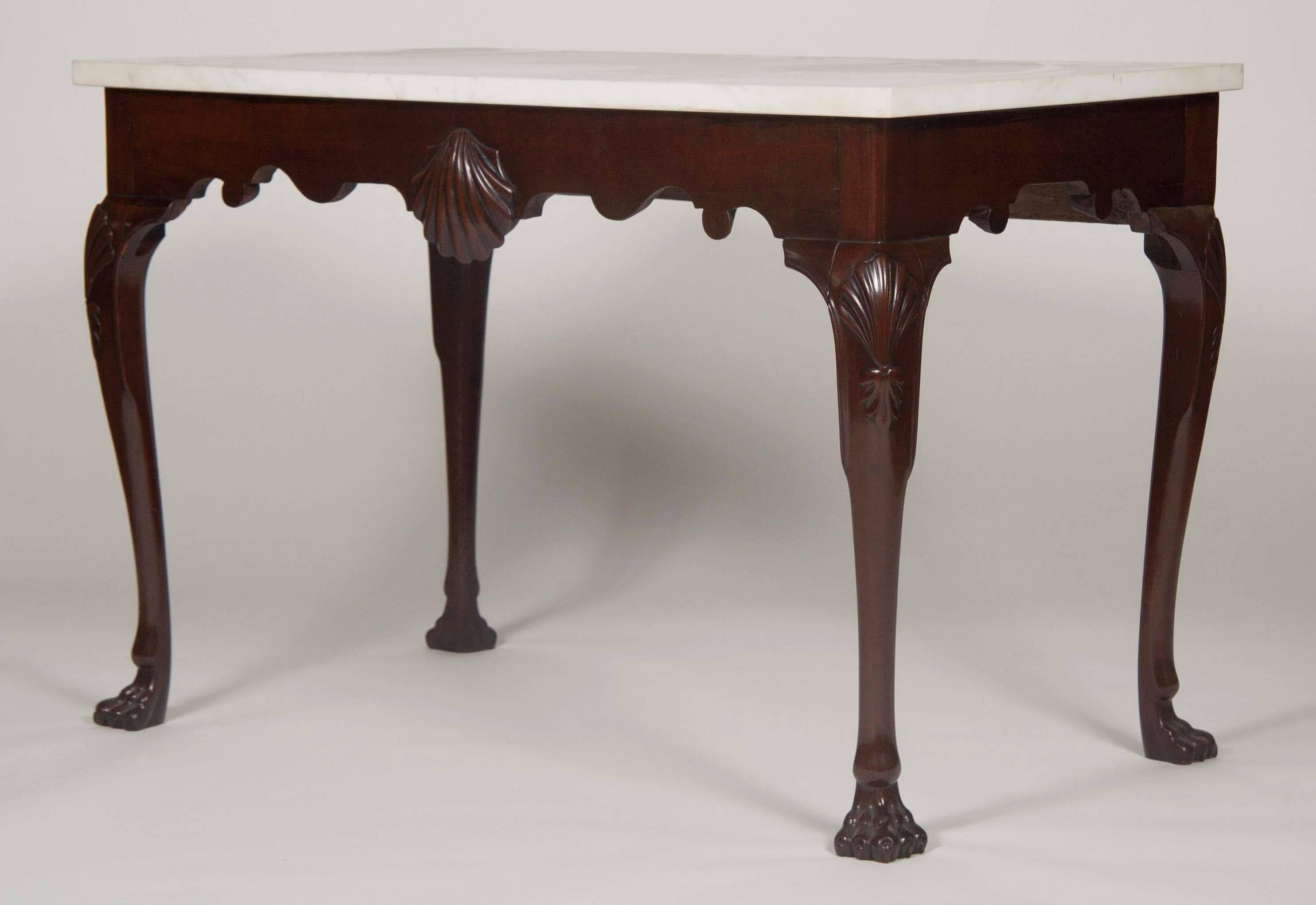 A very elegant 19th century Irish Chippendale style solid mahogany console table with a finely carved scallop shell decoration on the skirt, on four cabriole legs with shell and pendant bell flower carving to the knees, supported by paw feet. Rich