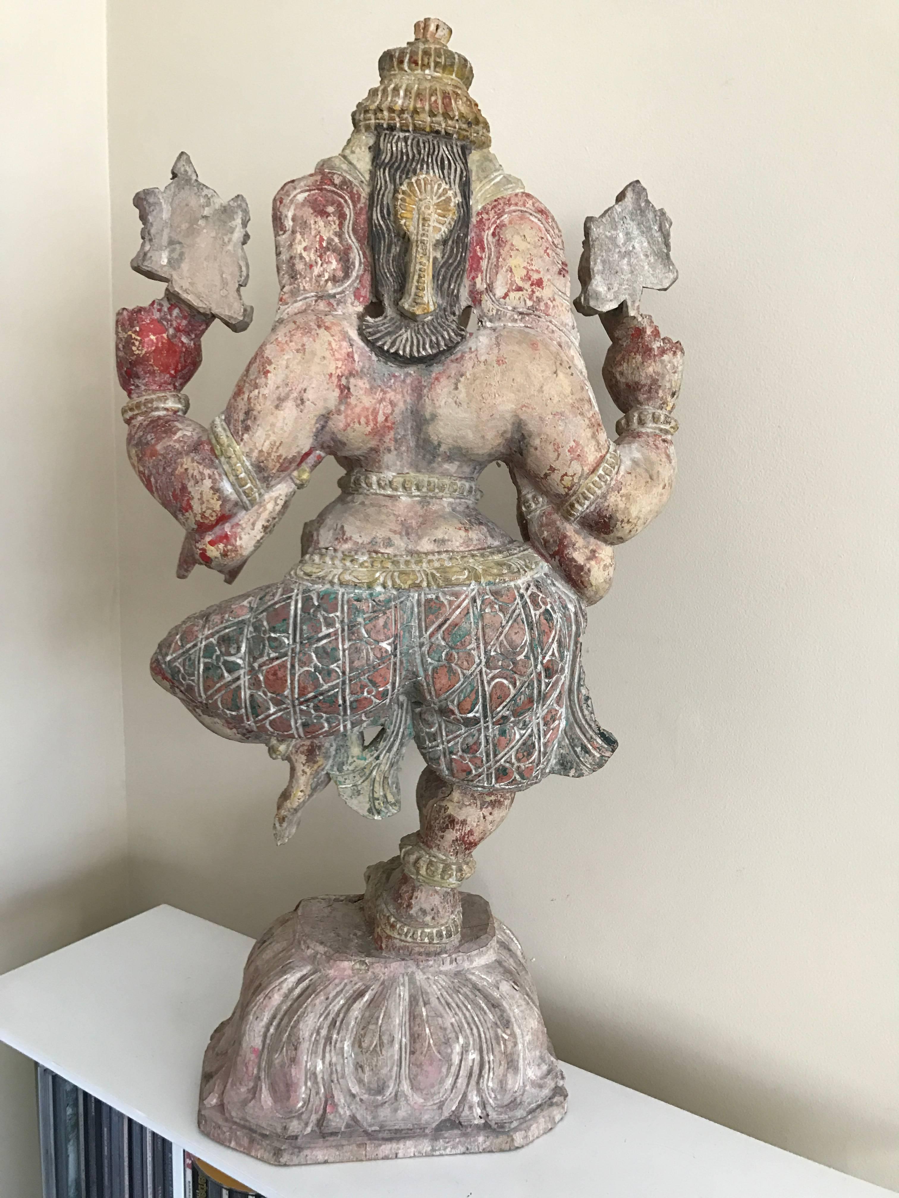 A beautifully carved figure of the dancing Ganesh depicted balancing on one leg on a lotus leaf plinth holding a different attribute in each of his four hands. The faded traces of original paint only serve to enhance the subtle beauty of this