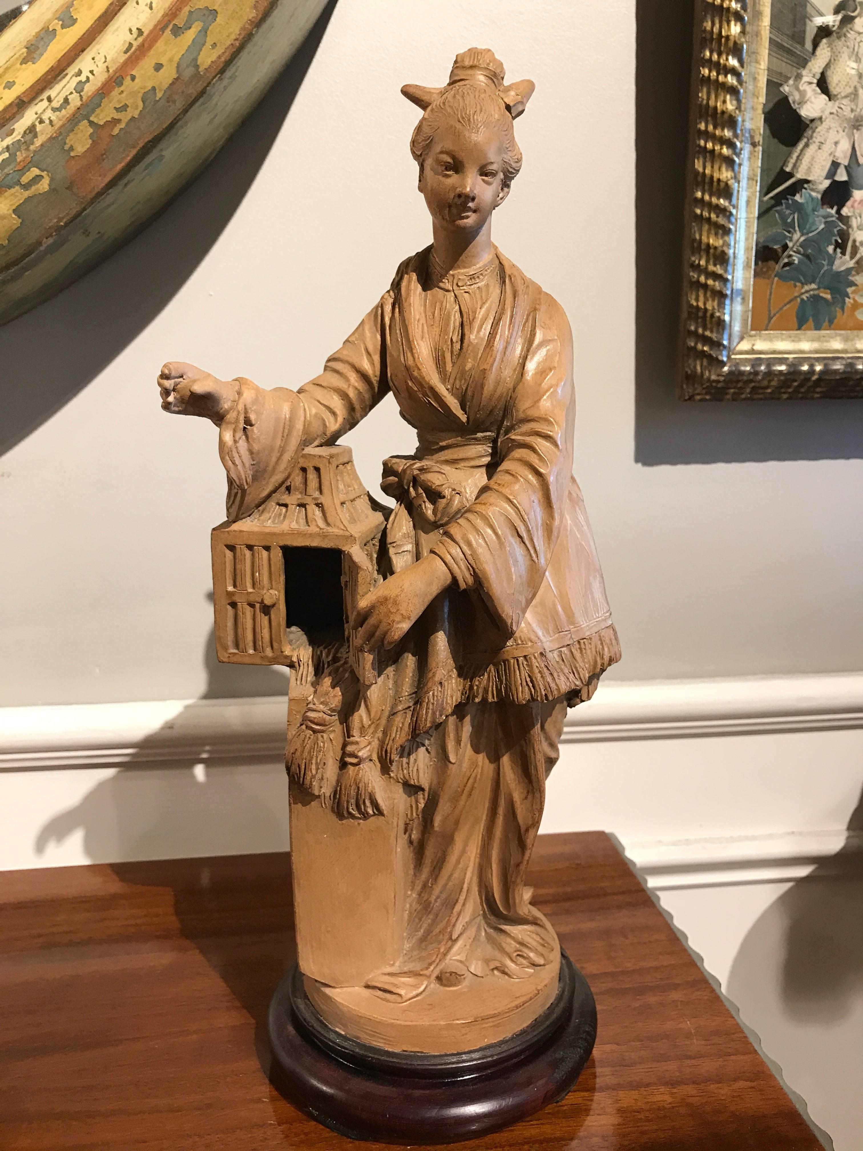 Pair of French Rococo style terracotta figures of bird sellers, a male and female, both holding bird cages. Both on mahogany bases.