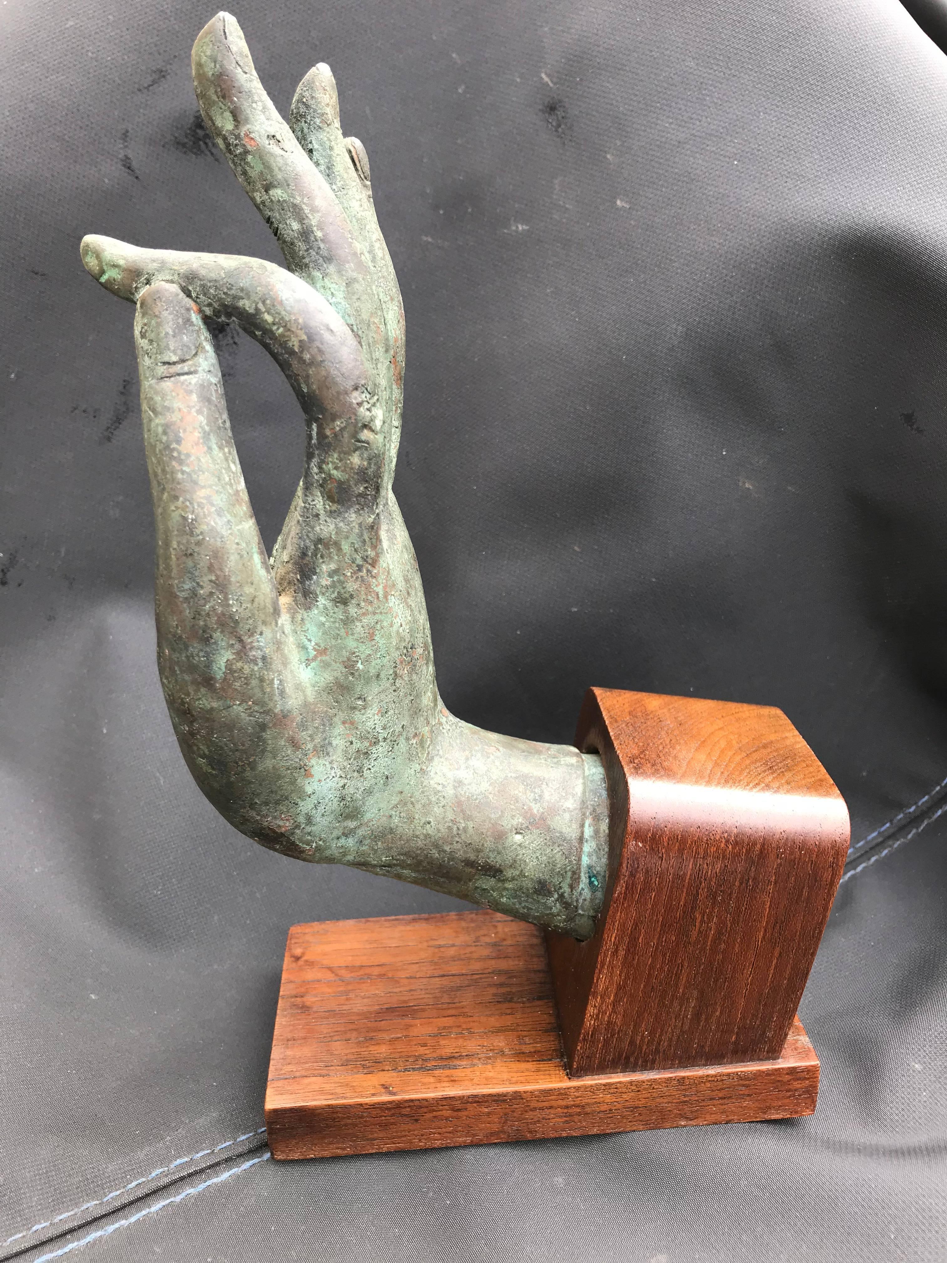 Beautifully realized bronze hand of Buddha, in the Vitarka mudra, mounted on a walnut base. Nice verdigris patina. 19th century, possibly earlier. Great gift for the yogi in your life. 
The Vitarka mudra symbolizes teaching and discussion. It shows