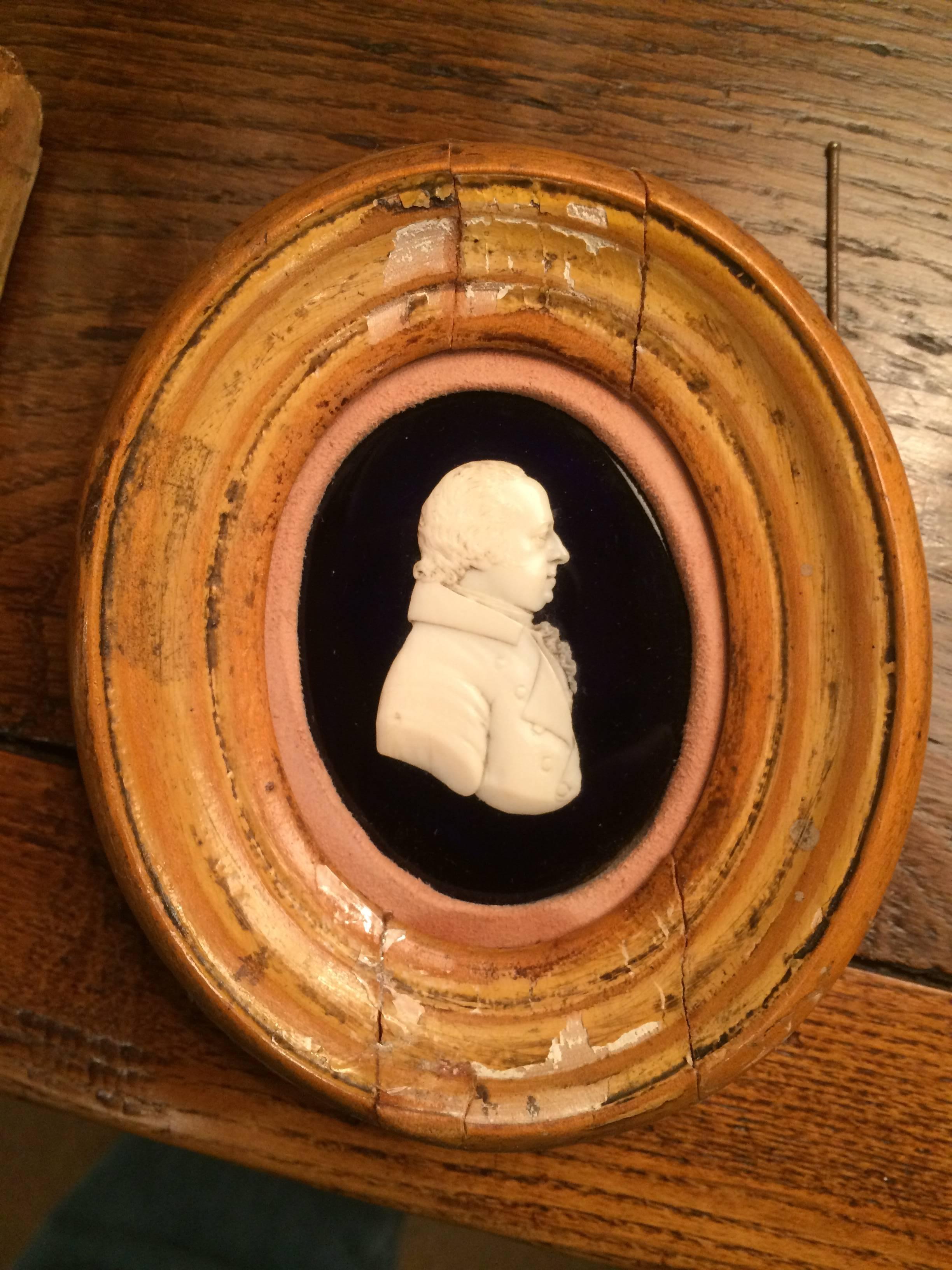 Very fine English early 19th century carved bone portrait of a nobleman or sea captain laid down on black glass and set in an oval walnut frame with an unusual suede mat. The gentleman shown in right profile wearing a collared coat with a ruffled