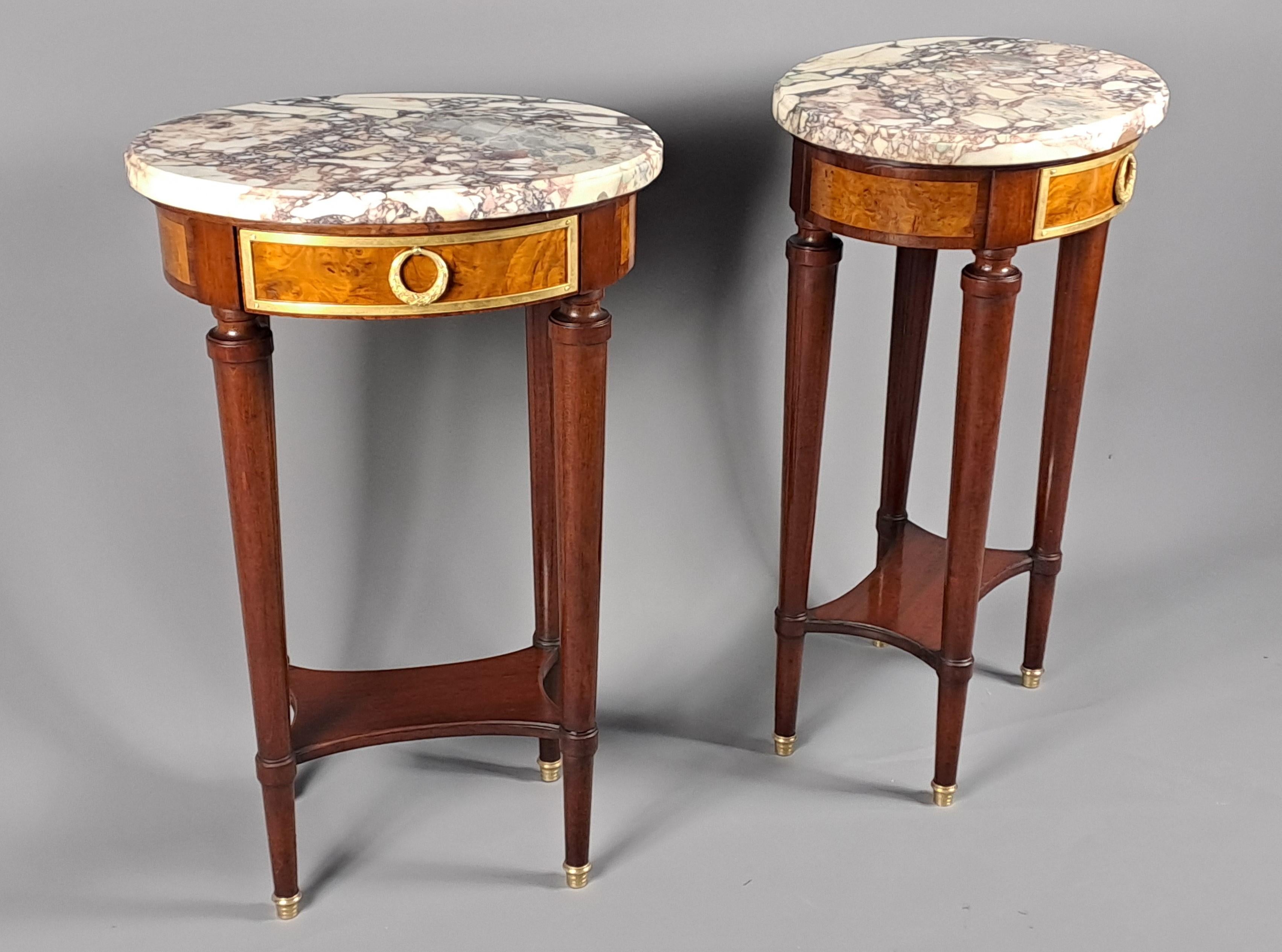 Paire de tables d'appoint de forme ovale en acajou et placage de loupe, ornementation de bronze doré, ouvrant un tiroir en façade, surmontées d'un beau marbre breccia à moulure cavetto.   

Entretoises formant des étagères.   


Travail de qualité