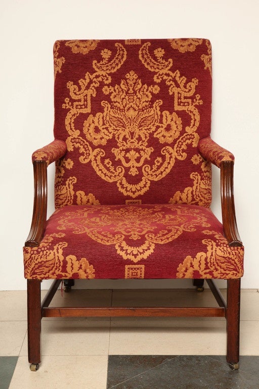 A pair of George III mahogany Gainsborough chairs with straight legs joined by stretchers and ending in brass casters.