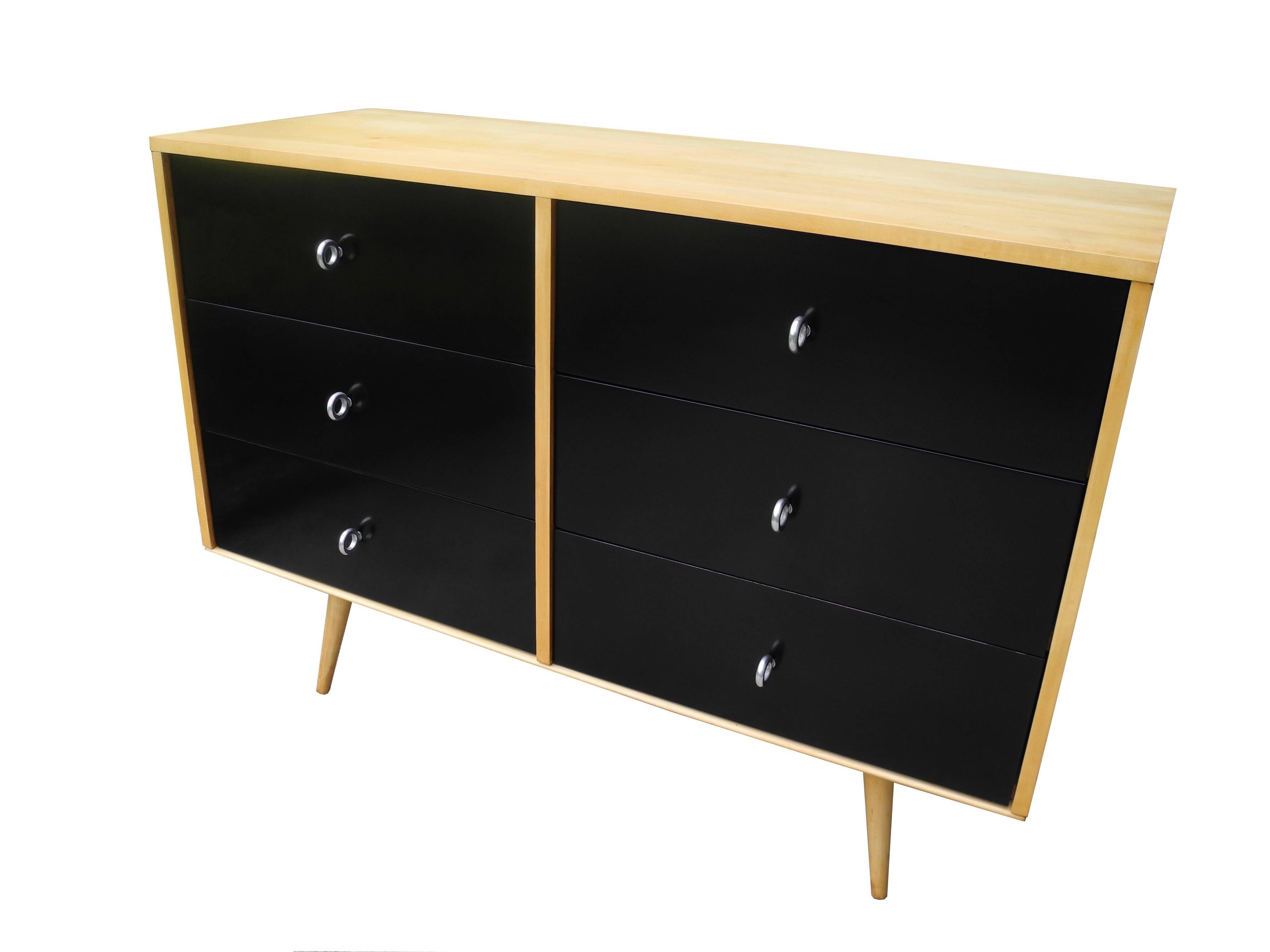 This Paul McCobb dresser has six drawers with original ring pulls. The solid maple case sits on top of a solid maple bench. Part of McCobb's modular designs. The drawer fronts are painted and polished black. The case and bench are natural maple.