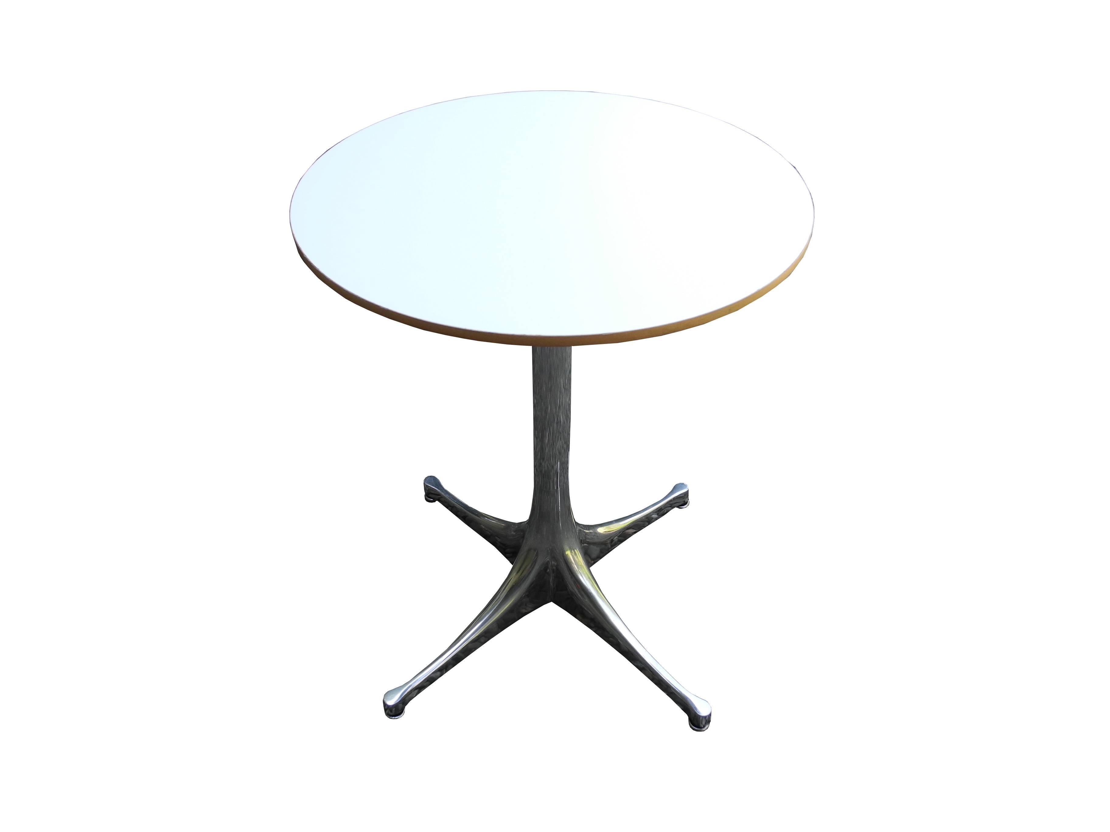 This 17" diameter, 21.5" tall, modern design polished aluminum base with white laminate top and wood trim is a George Nelson Classic. Designed in the 1950s and manufactured by Herman Miller this particular table was made in the 1980s.