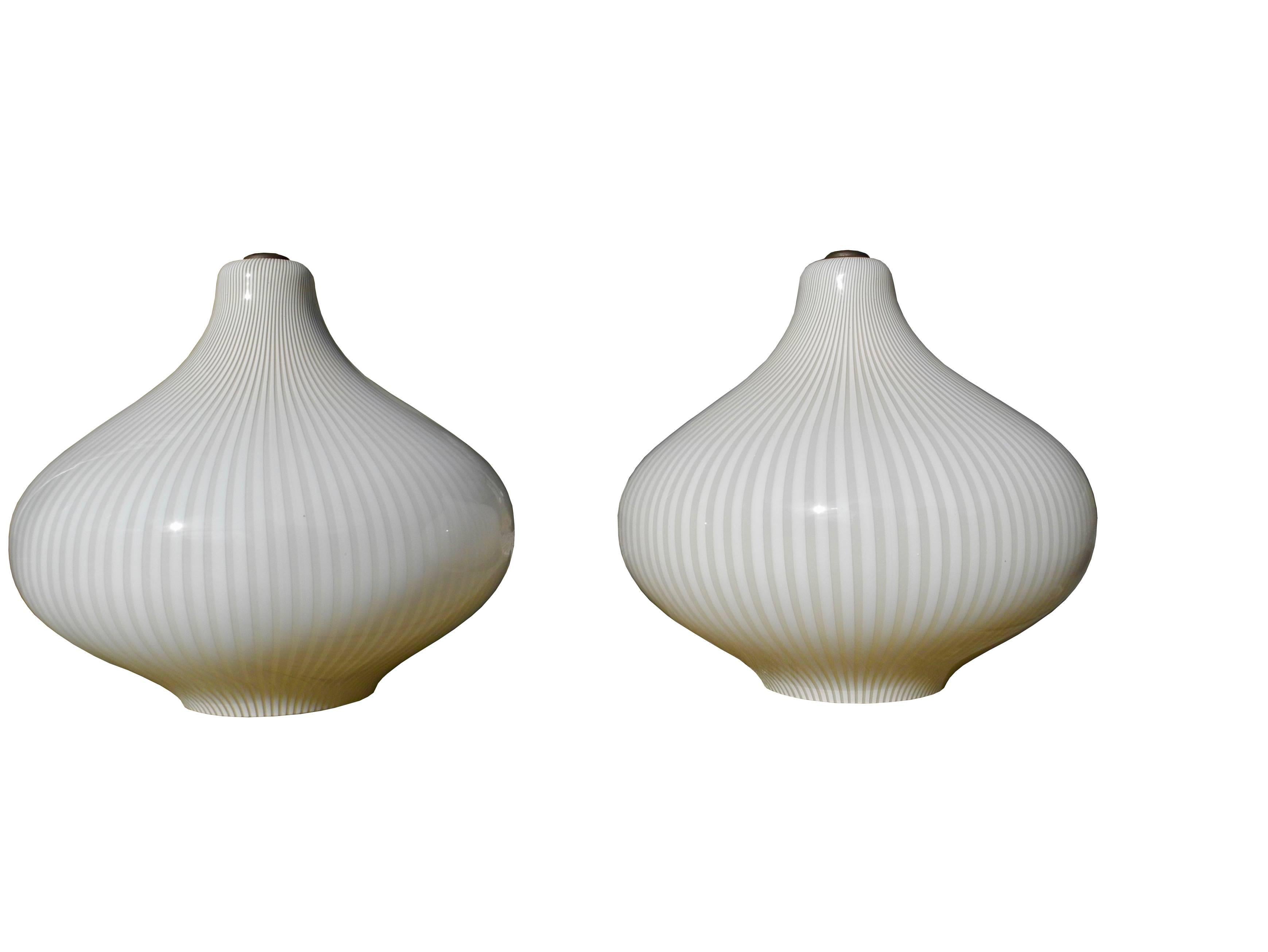 This pair of Venini glass pendant lamps were designed by Massimo Vignelli in the 1960s.
The glass is of a tan and white color and both onion lamps are in perfect condition. No chips in the glass.