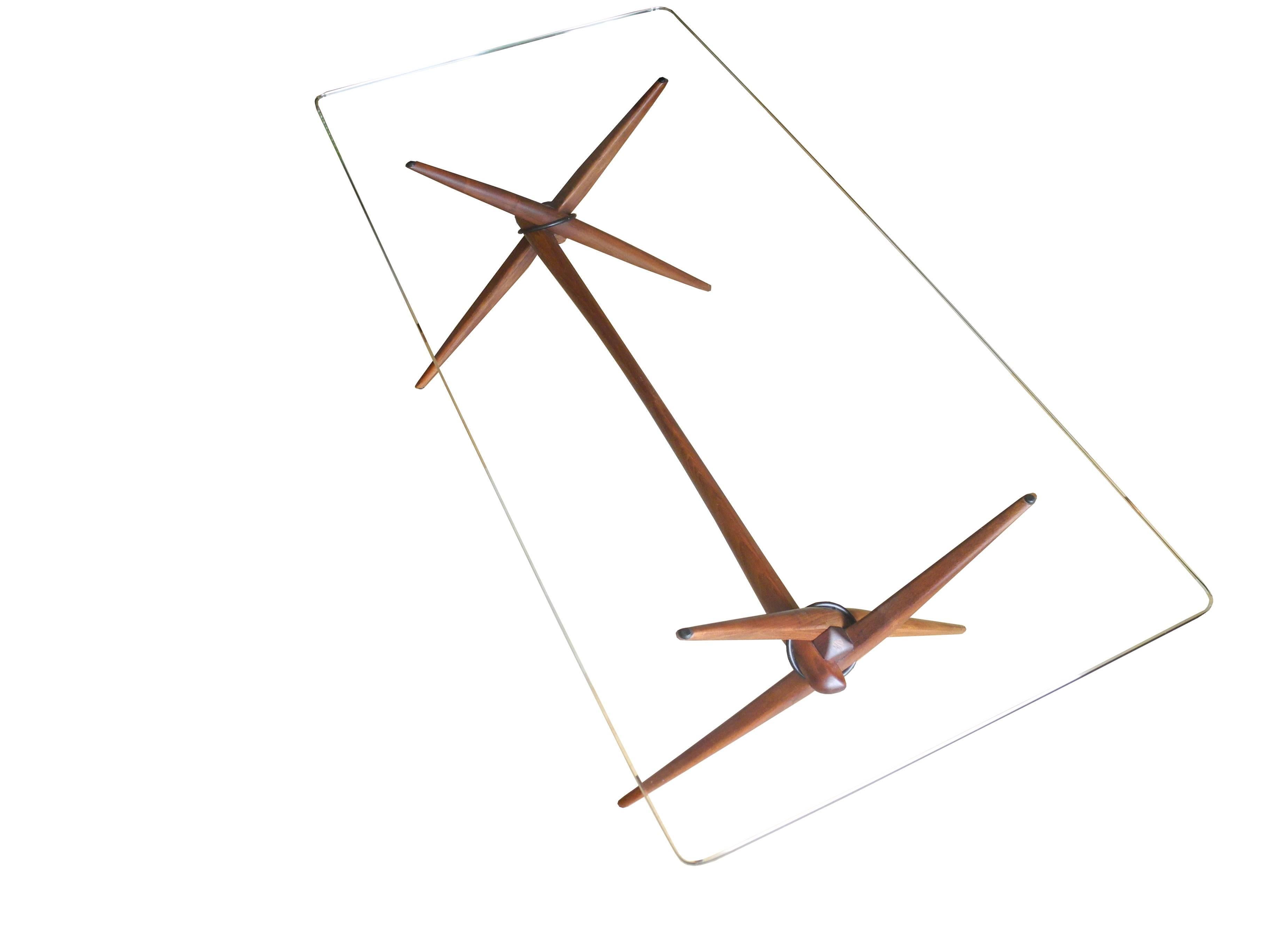 This 1950s walnut coffee table designed by Guy Barker is a sculptural design original. Using a metal ring, three arms, a nut and a bow centre bar the design is delicate yet withstands a lot of weight. This piece was found it its original condition