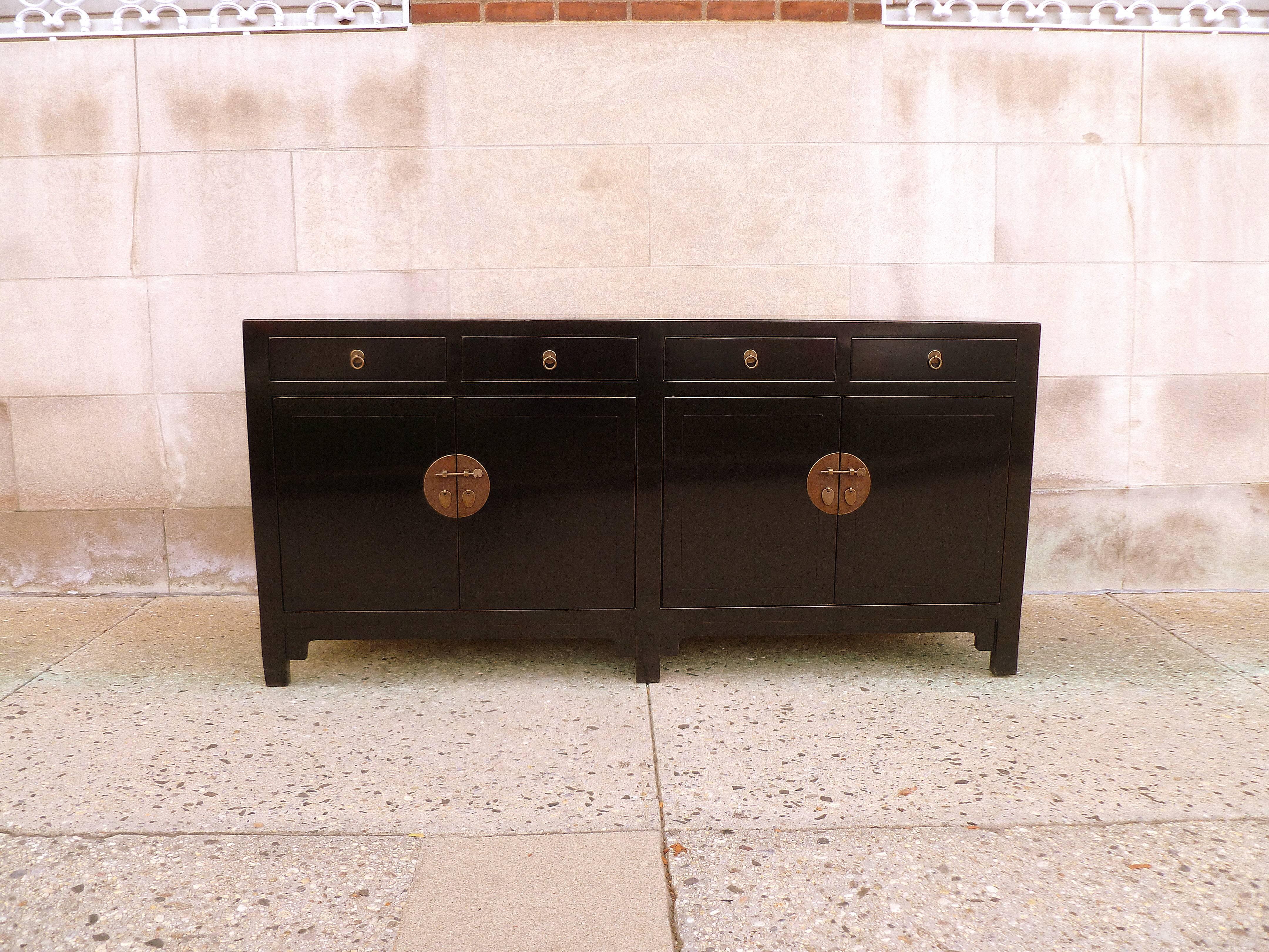 A refined and elegant black lacquer sideboard with four drawers on top of two pairs of doors, brass fitting, beautiful color, form and lines.