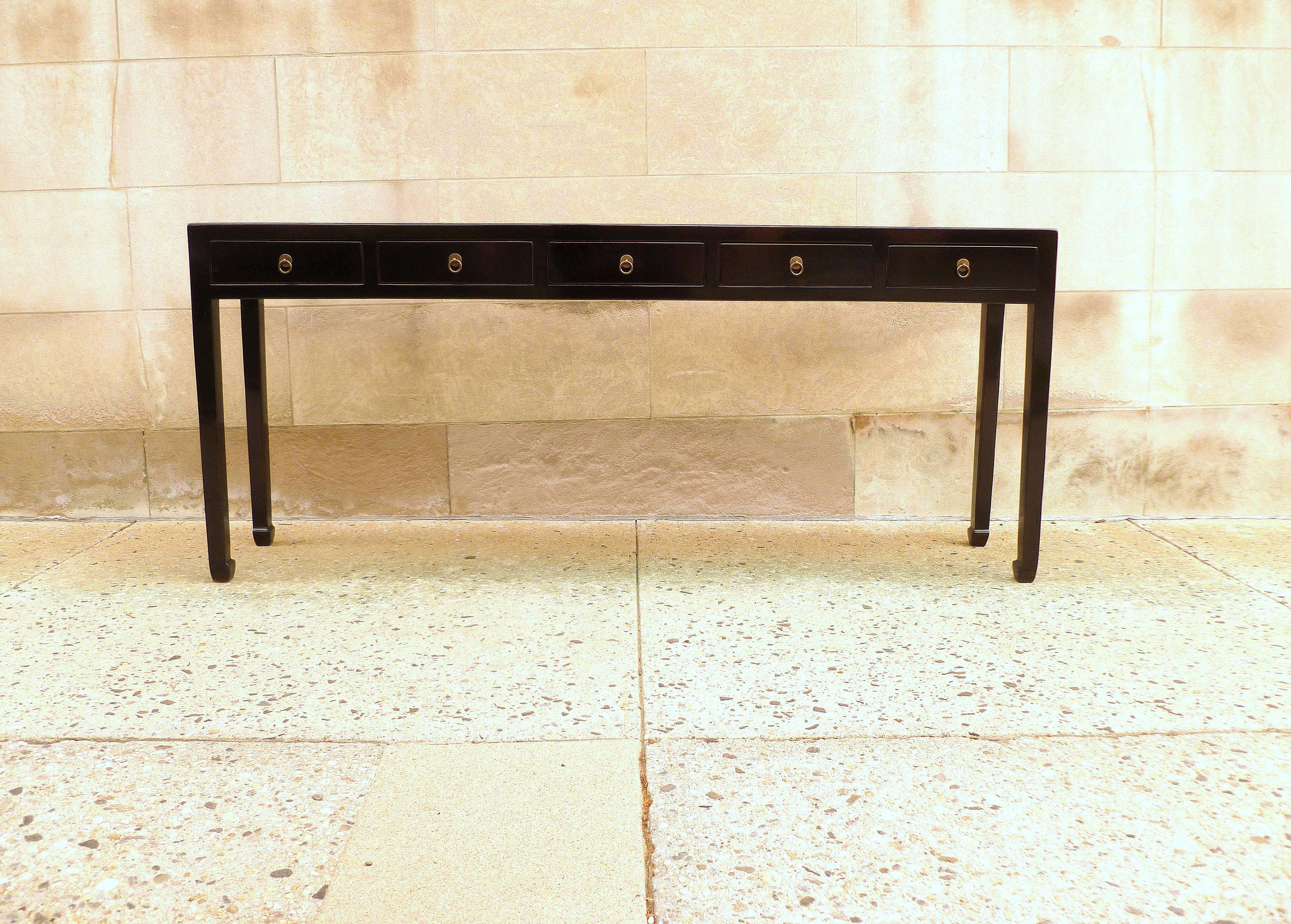 A fine black lacquer console table with five drawers, framed top supported by straight legs with drawers and brass ring pulls.
