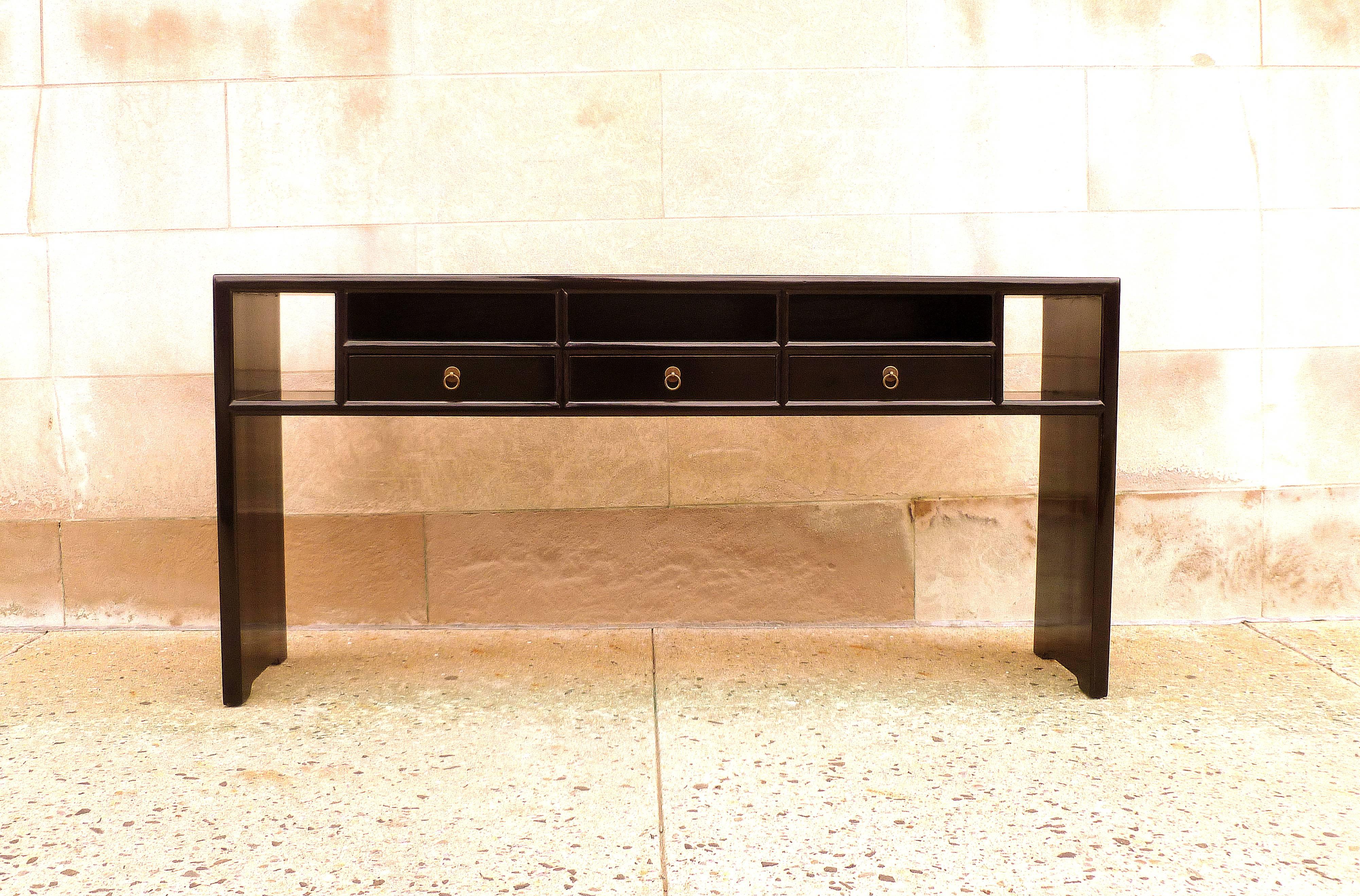 Fine black lacquer console table with waterfall legs, three drawers and open spaces. Very elegant and beautiful piece.