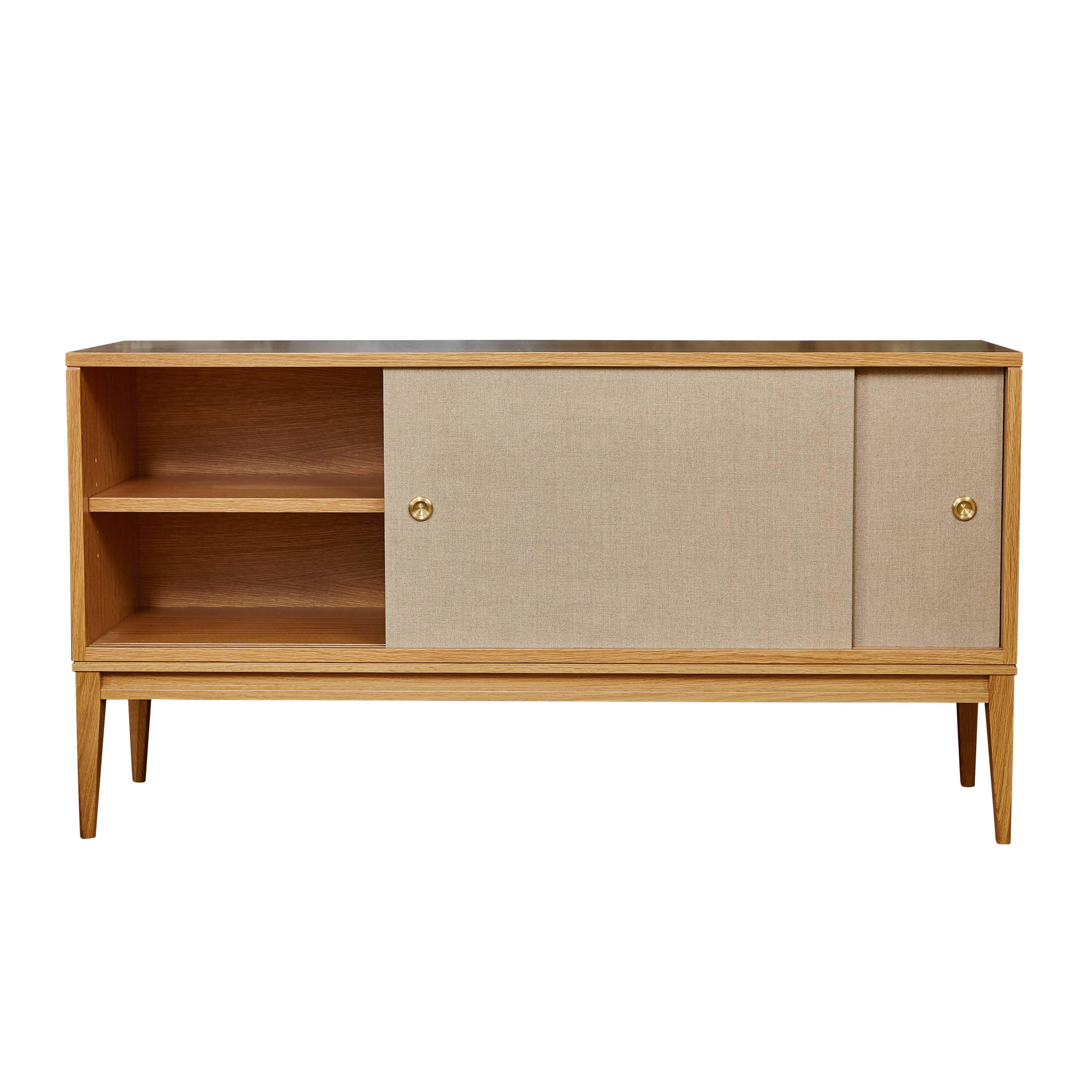 MN originals cerused oak console on solid tapered leg base with Belgium linen sliding doors detailed with solid brass finger pull hardware. Interior has adjustable shelving and cerused finish to match exterior. Please contact us about custom sizes