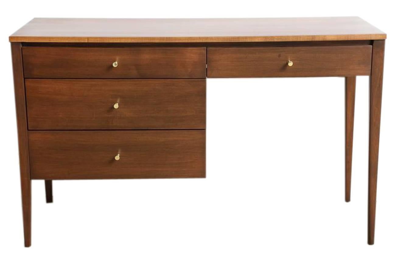 Paul McCobb four-drawer walnut Planner Group desk, circa 1955 in fully restored condition. Solid maple construction finished in a warm walnut tone with original brass drawer pulls.