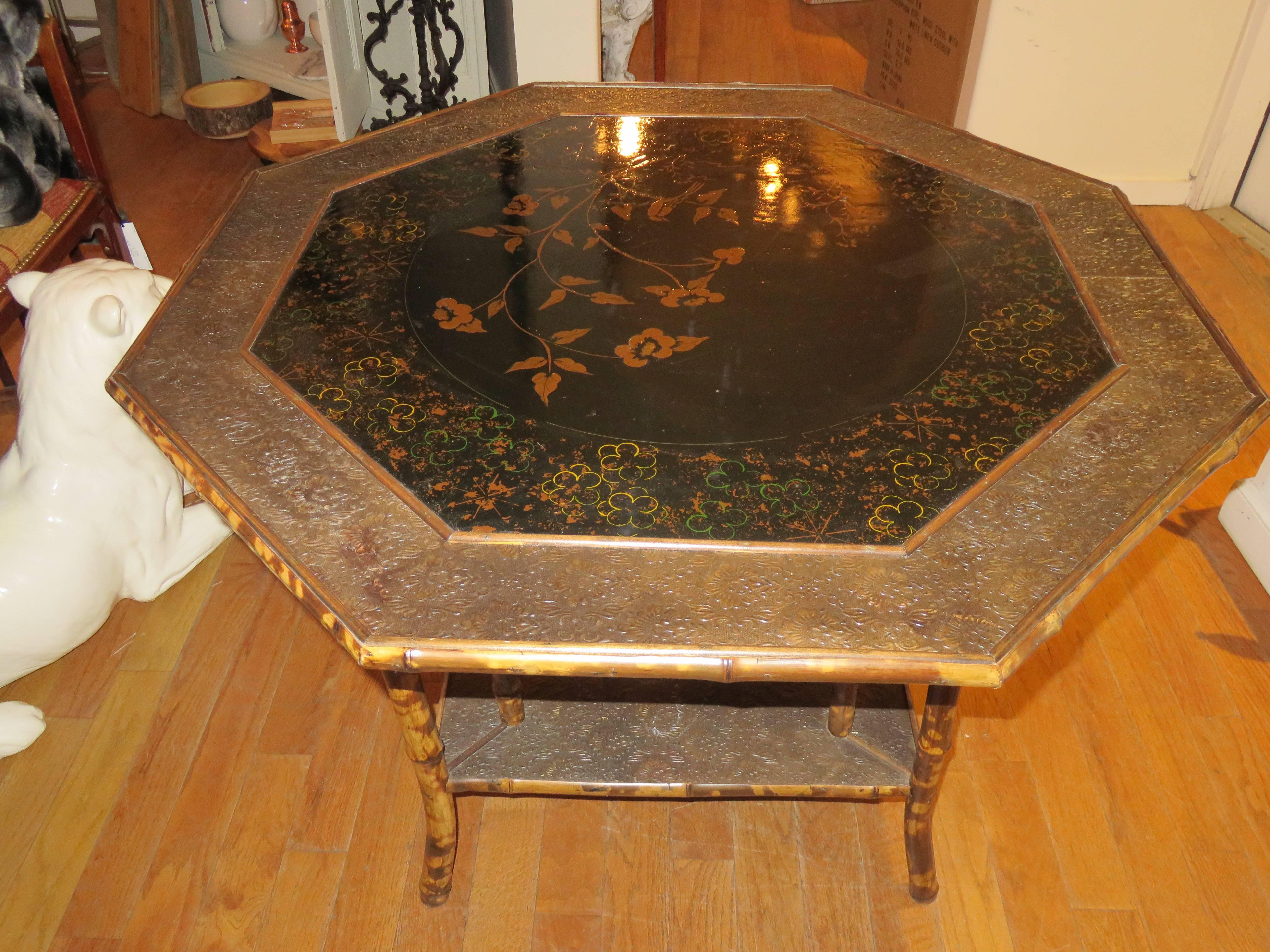 A late 19 century Anglo-Indian/British colonial octagon shaped center table. With a beautiful chinoiserie top. A stamped leather trim on top and bottom level.
 Faux tortoiseshell bamboo frame, lovely condition considering the age.