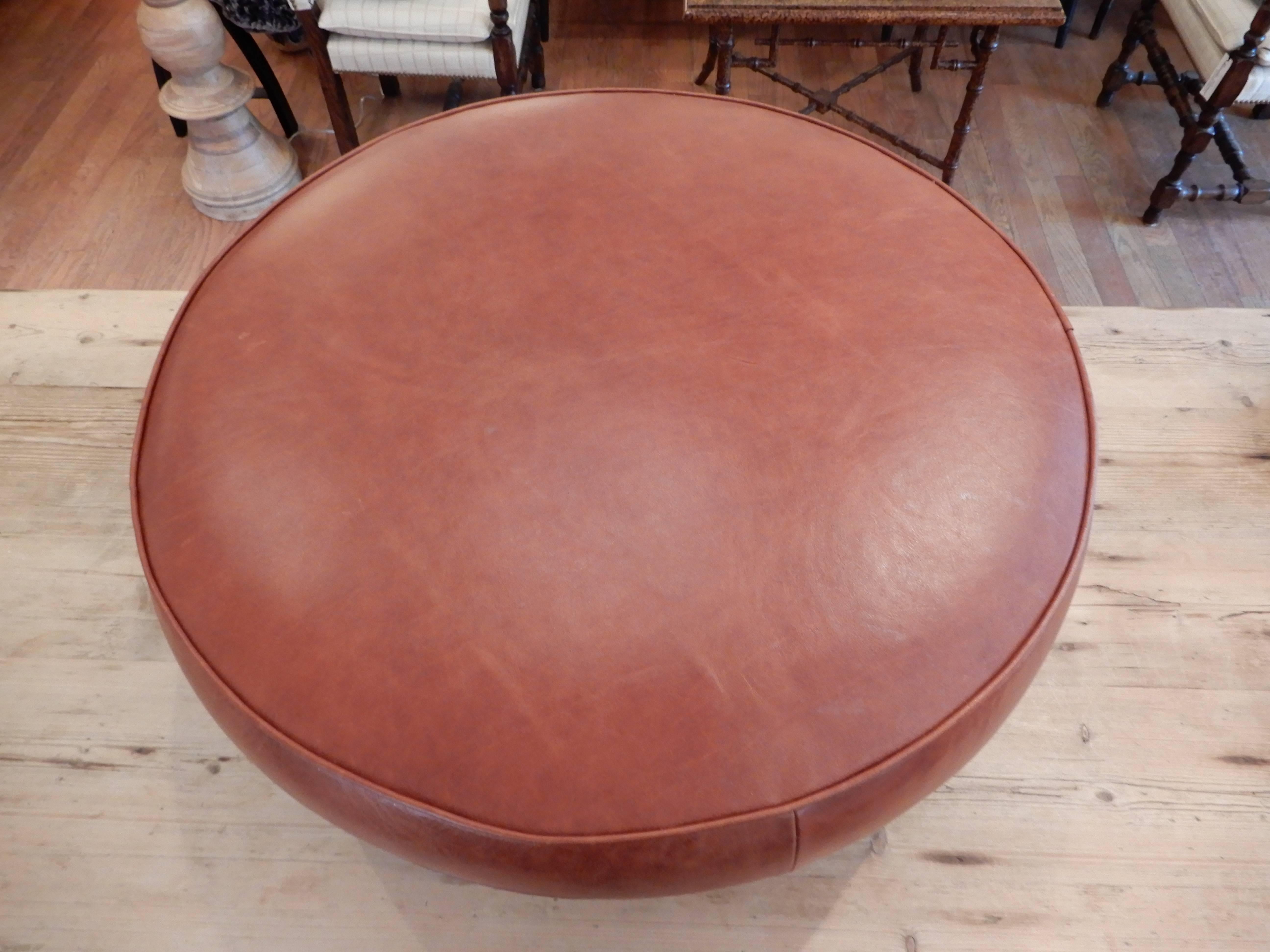 A Danish Mid Century Modern low ottoman or stool,measuring 30 inches round and 11 inches high,flat enough for a tray top.
New premium leather in a rich  cognac brown,wood legs with bronzed metal feet.