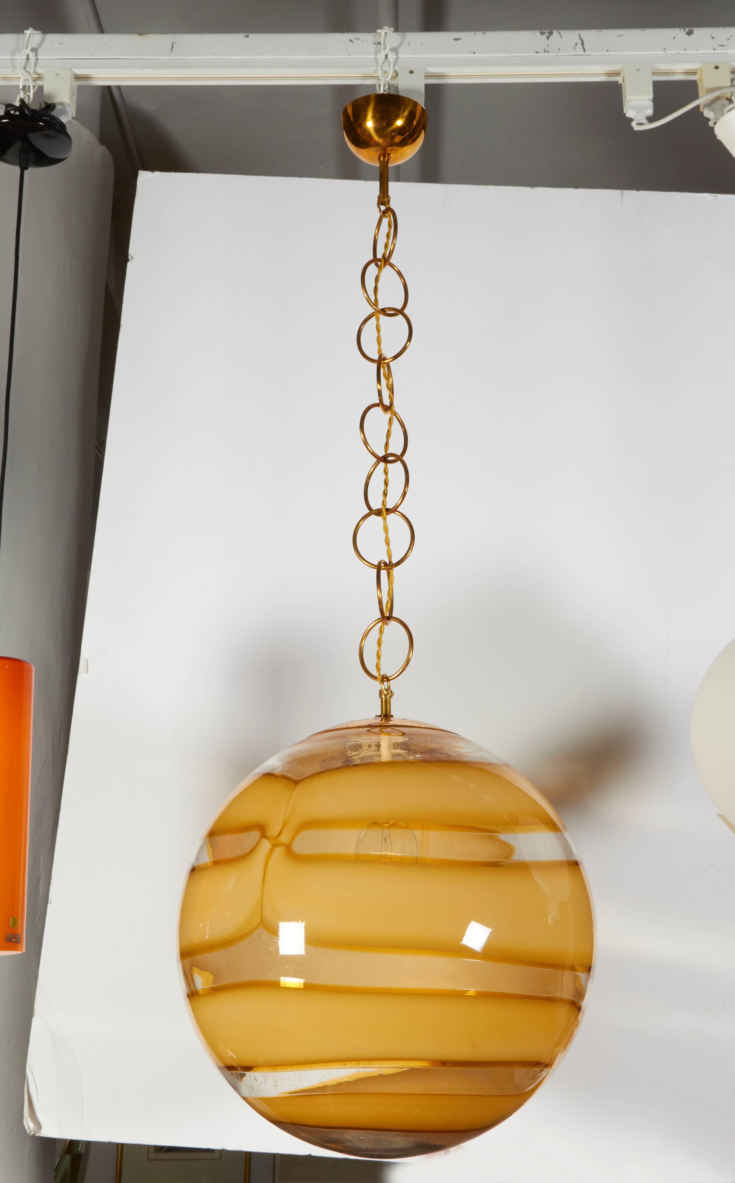 A Classic Murano globe pendant with rich amber coloring and superior brass hardware. The length of the chain can be adjusted to your needs.