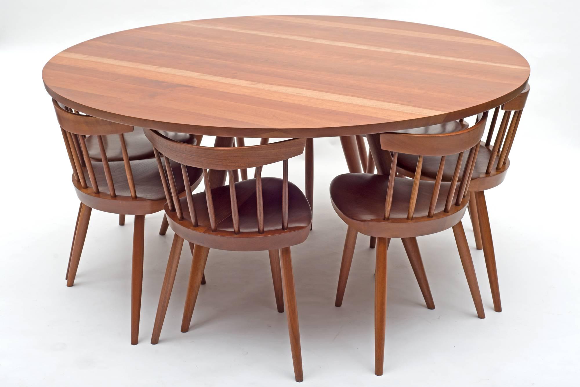 One of George Nakashima's Classic dining table designs with nine Mira chairs eight of which fit under the tabletop. The set is in wonderful restored condition.