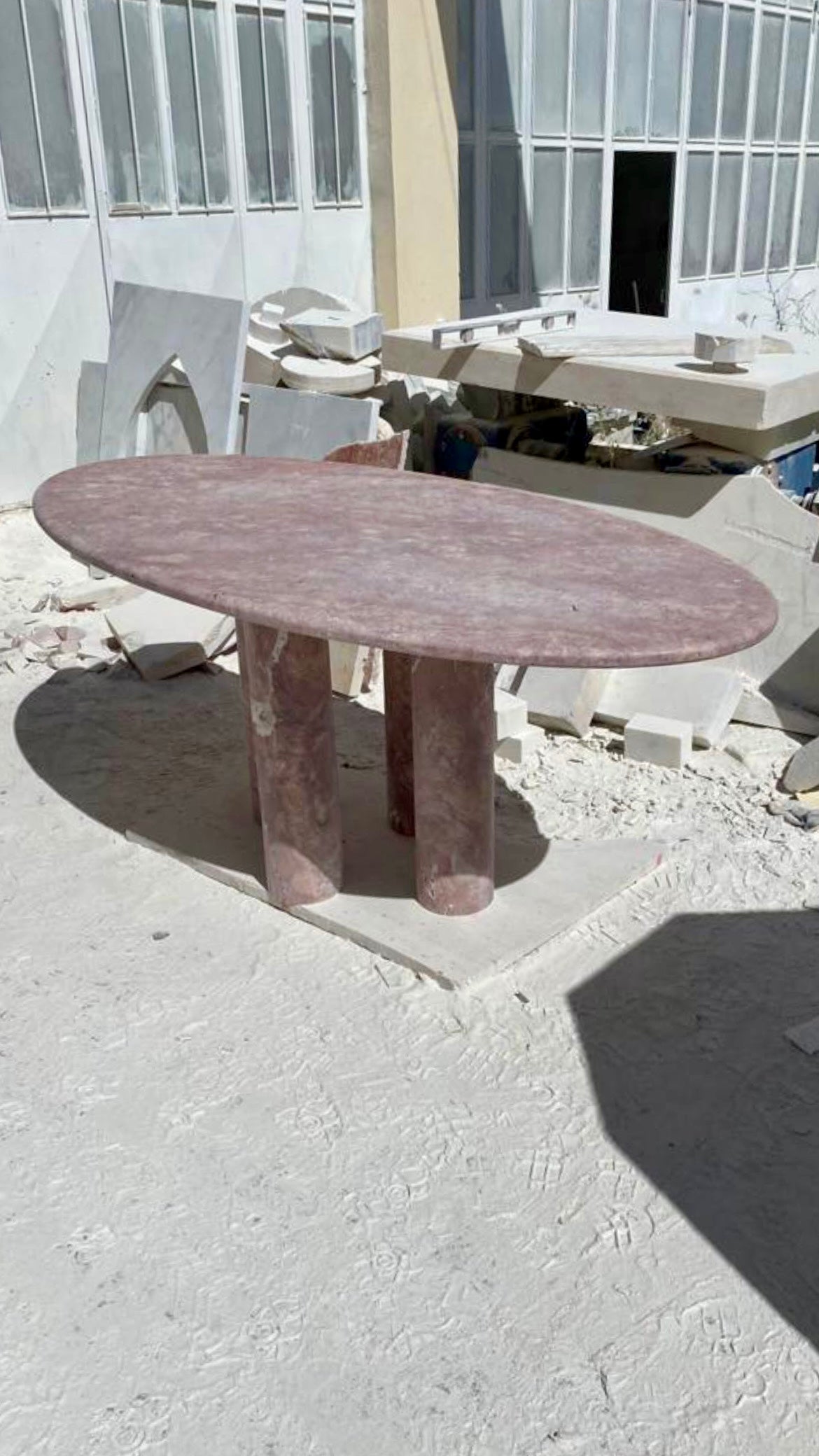Dieser minimalistische Tisch besteht aus einem einzigen Material und hat eine Platte mit geschwungener Kante, die elegant auf vier zylindrischen Säulen ruht, was dem Tisch einen skulpturalen Charakter verleiht. 

Die geschliffene, matte Oberfläche,