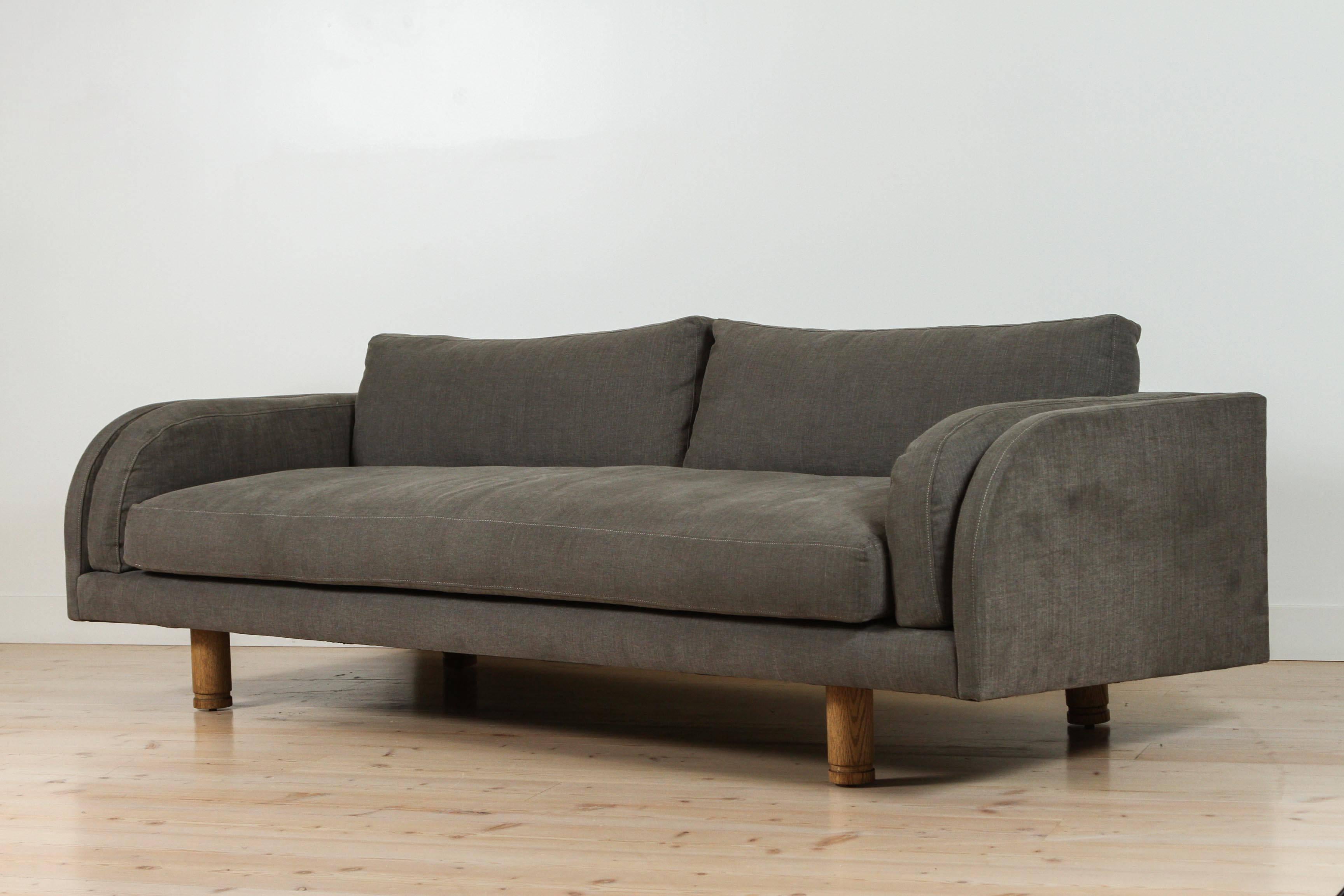 The Moreno Sofa sits low and deep with Italian inspired curved arms. The sofa features loose seat and back cushions and two side cushions that mimic the curvature of the arms. The legs have an incised detail and are made of solid American walnut or