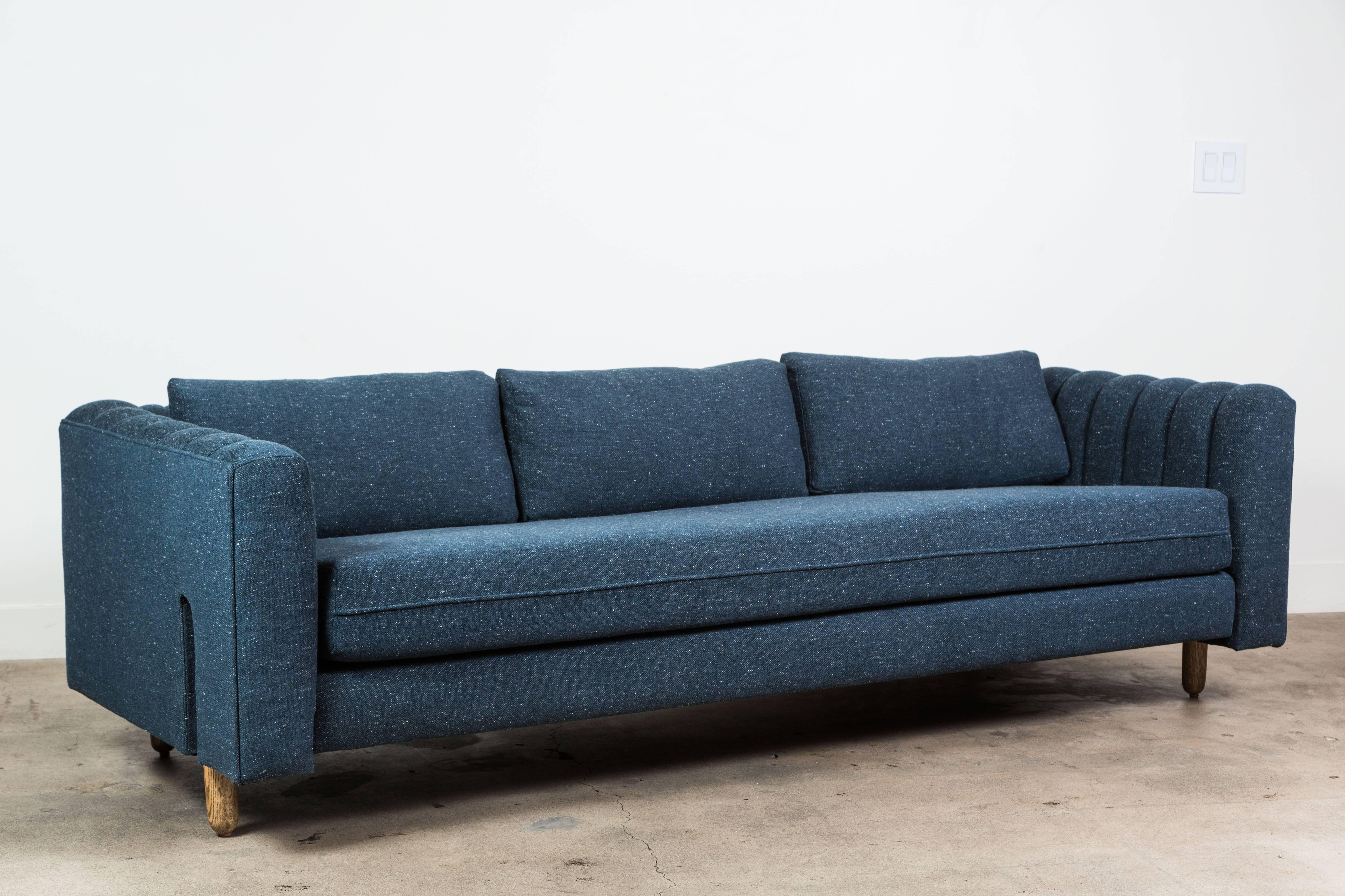The Isherwood Sofa features a channel tufted body with loose bolster cushions. The turned legs are made of solid white oak or American walnut and are inset on the sides revealing the leg detail.

Available to order in customers own materials with a
