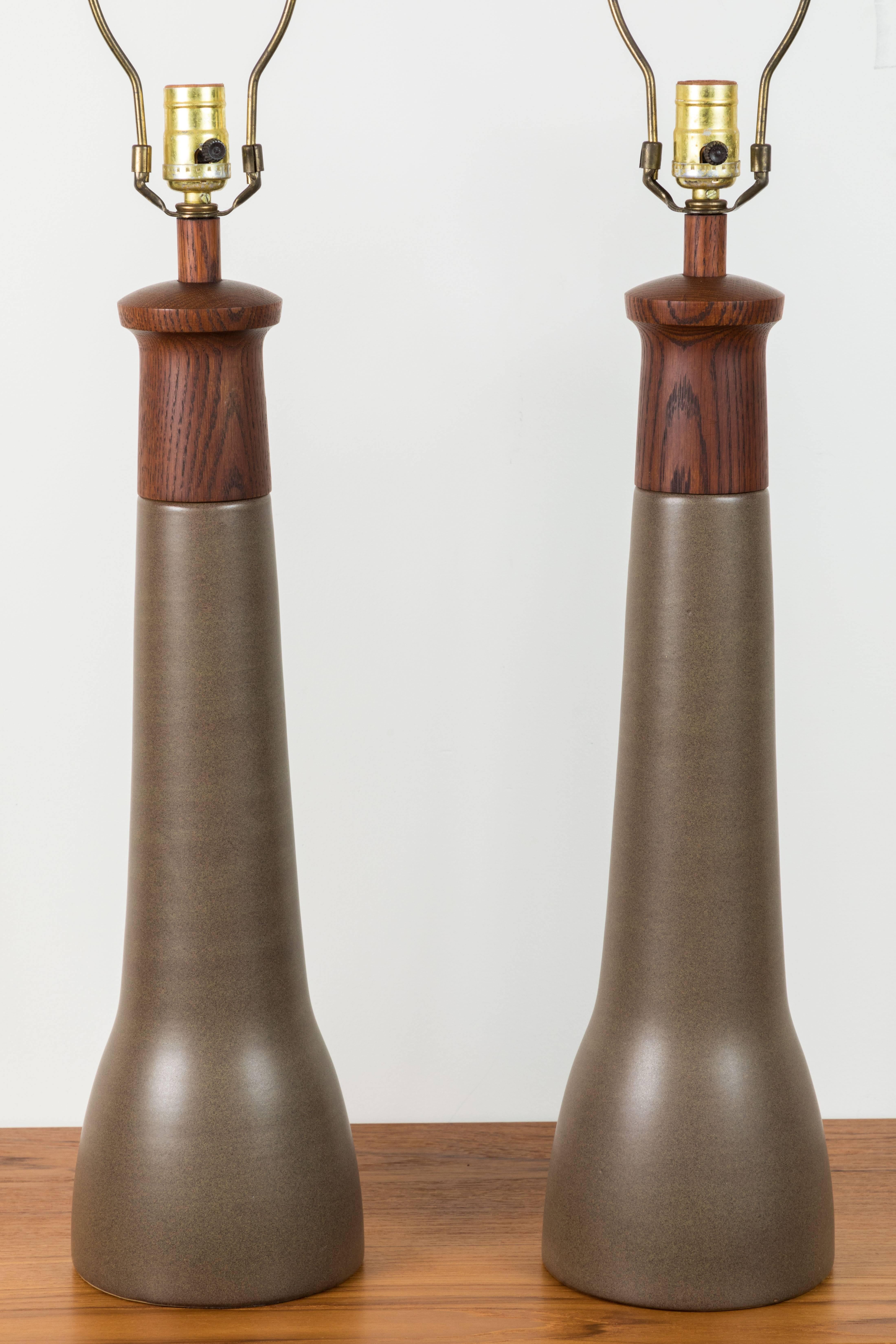 Pair of teak and ceramic lamps by Martz. Includes original teak finials. No shades.