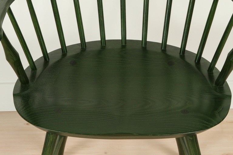 The Wayland Armchair features spindle details and hand-carved hands on each arm. Hunter green stain on Ash wood.
