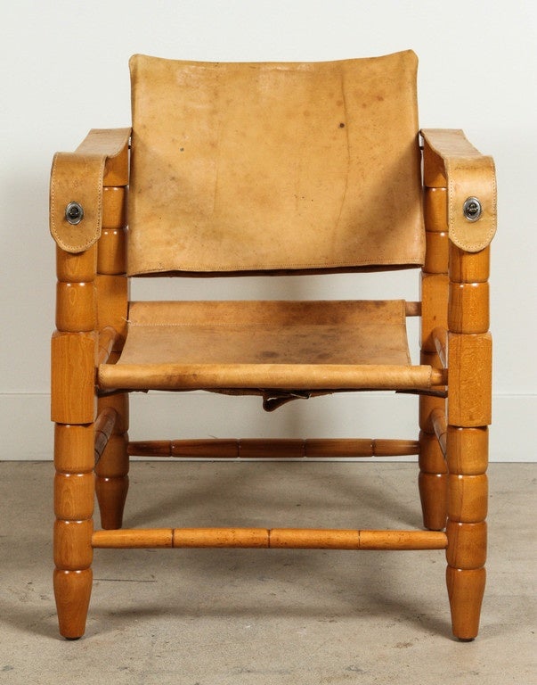 Pair of leather and oak safari chairs feature spindled legs and cross braces with original leather upholstery. Solid wood. Restored and conditioned.