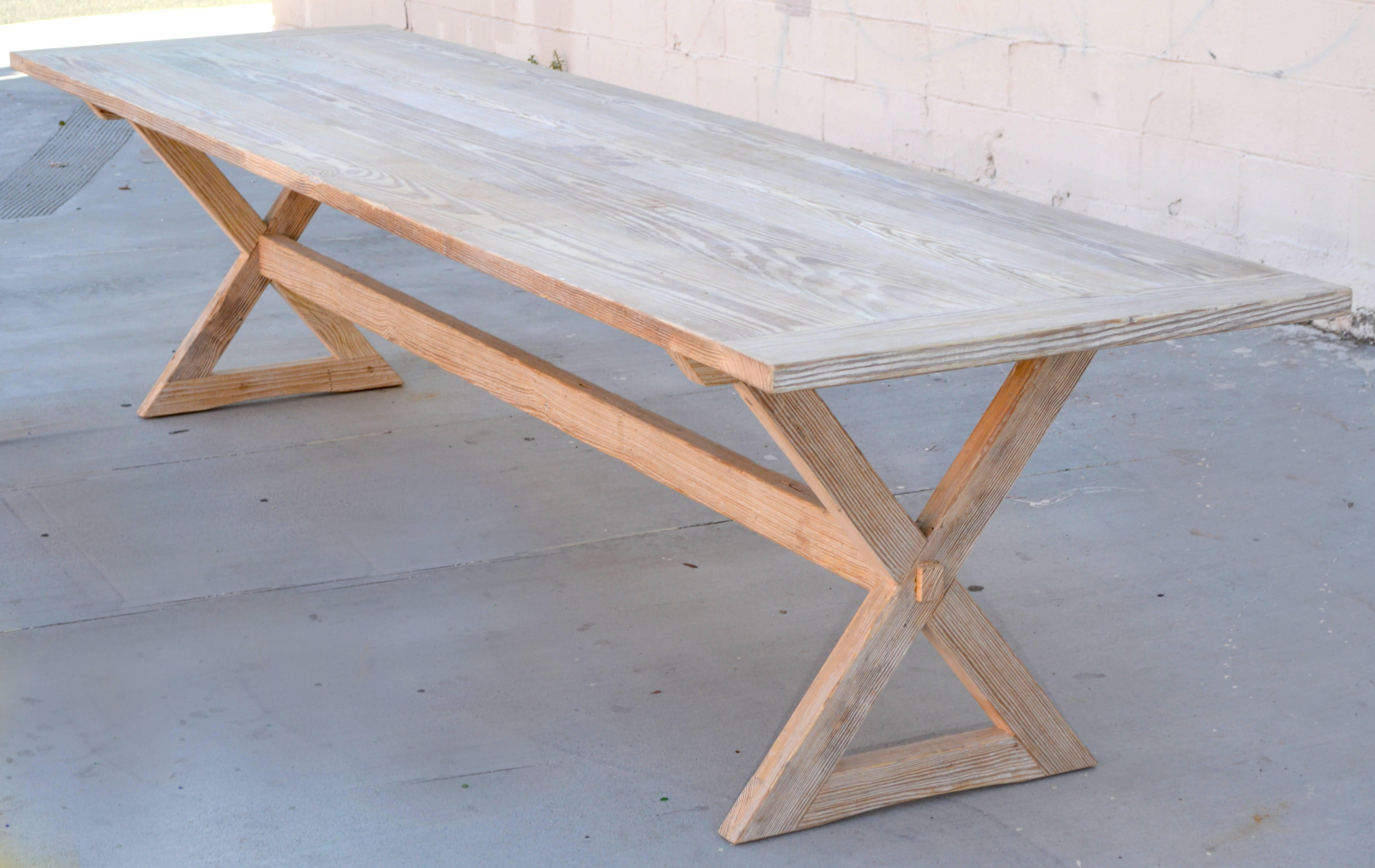 Cette table à tréteaux est fabriquée à partir de bois de pin massif recyclé, blanchi au soleil. Le plateau peut être retiré de la base en tirant sur la goupille ronde située au centre supérieur de chaque pied, juste sous le plateau de la table. Des