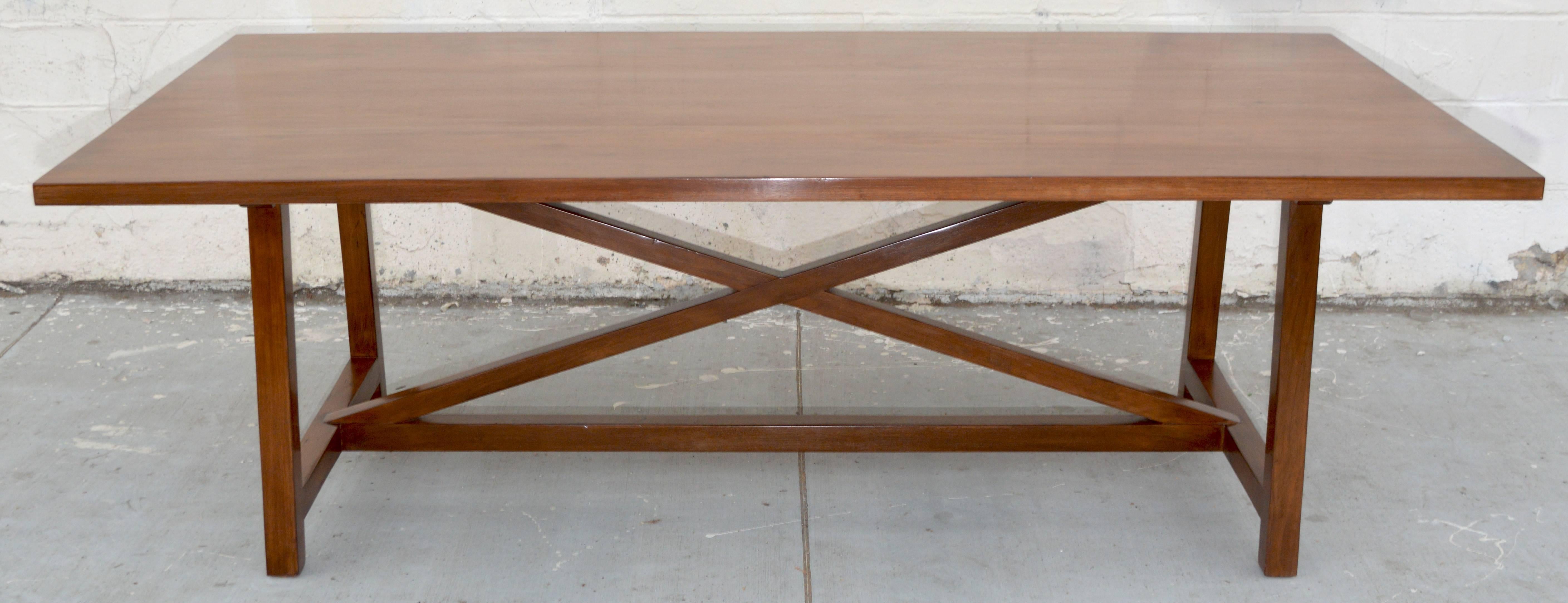 This custom dining table in walnut has splayed legs and stretchers crossed in an 'X', this table can be ordered with or without extensions. Shown here, this table is 114