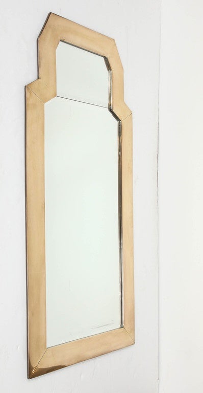 A tall shaped mirror frame in cast brass holds two hand-beveled mirror plates. By Chapman, dated 1981. Newly repolished, otherwise original.