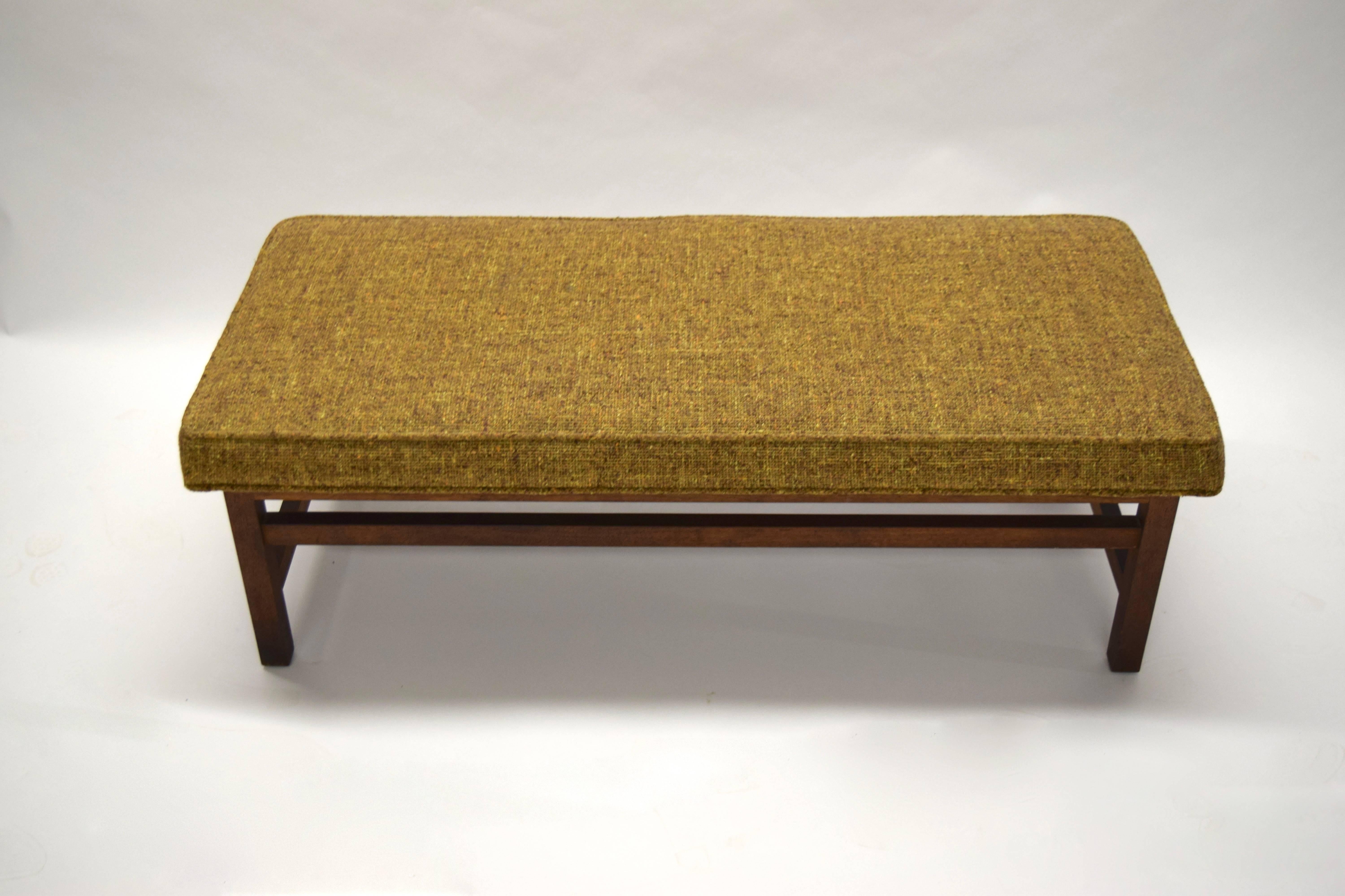 Bench in walnut with stretchers on all sides. At each end the stretchers are low close to the bottom and in front and back the stretchers are just below the seat. 
The seat has original fabric.