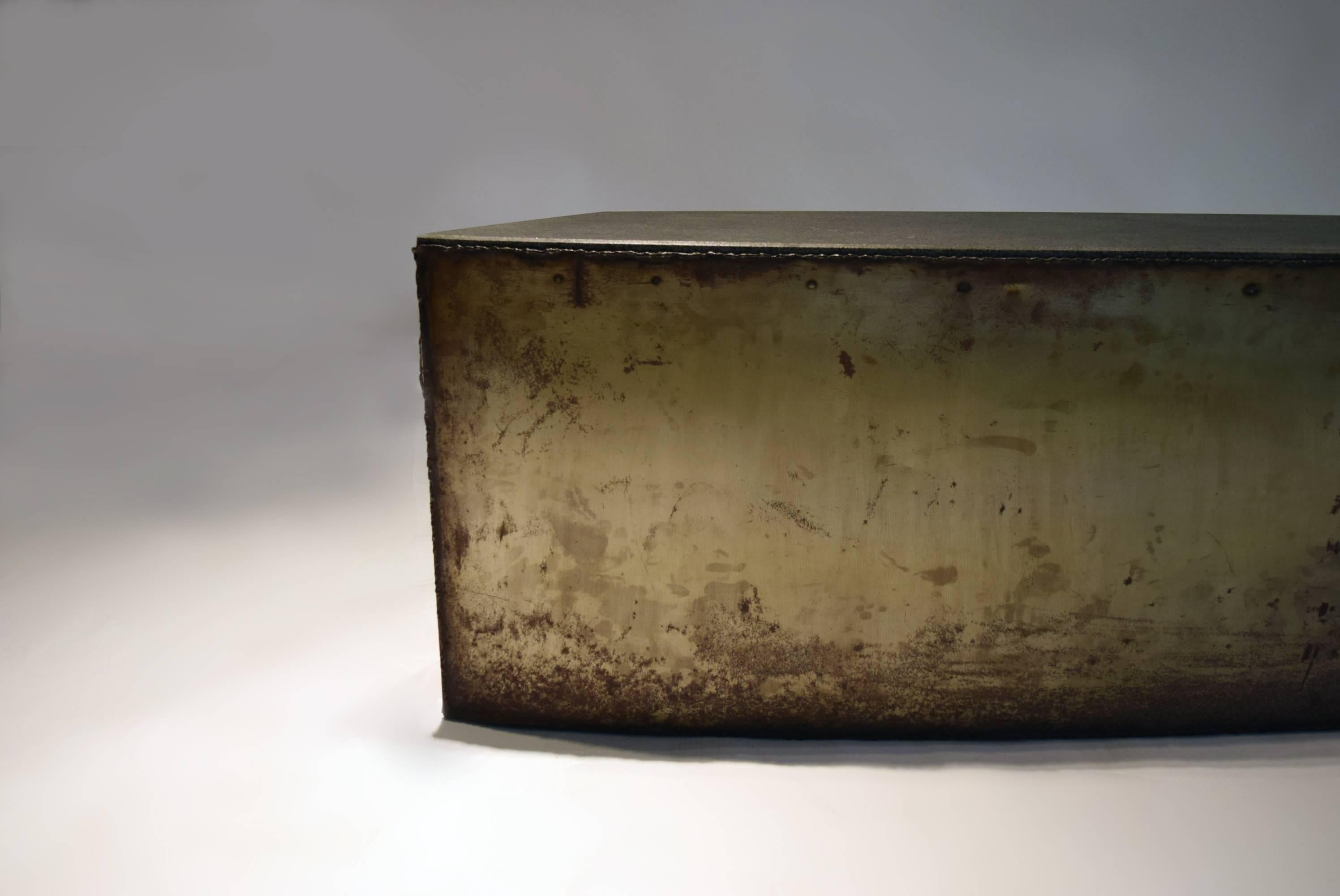 Narrow-depth brutalist table that can be used as a bench, cocktail table or coffee table, in acid washed metal with raw welding along the edges and an inset, honed granite top. 