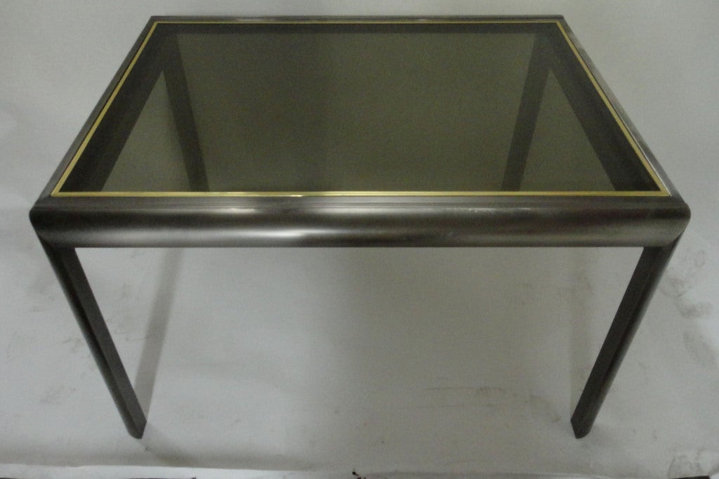Metal framed dining or display table that opens to double its size made of chromed metal with brass detail and smoked glass on both tops. Tabletop slides to one side exposing the additional top that slides in opposite direction both locking in at