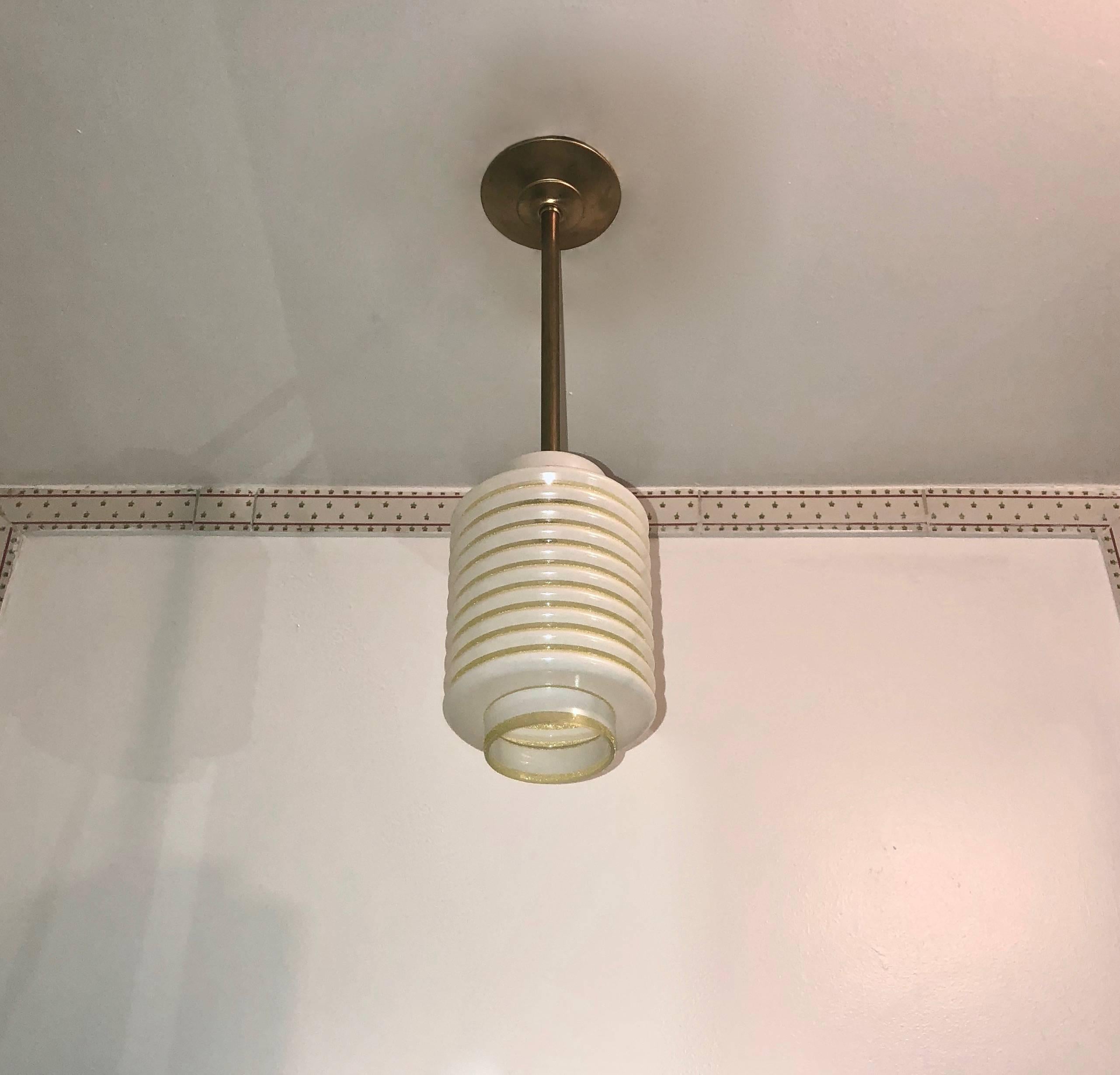 Five French ceiling lights made of ribbed glass with decorative yellow bands. Each light hangs from a 12 inch brass stem with canopy. The lights have been rewired with a single American candelabra socket.
Original label 