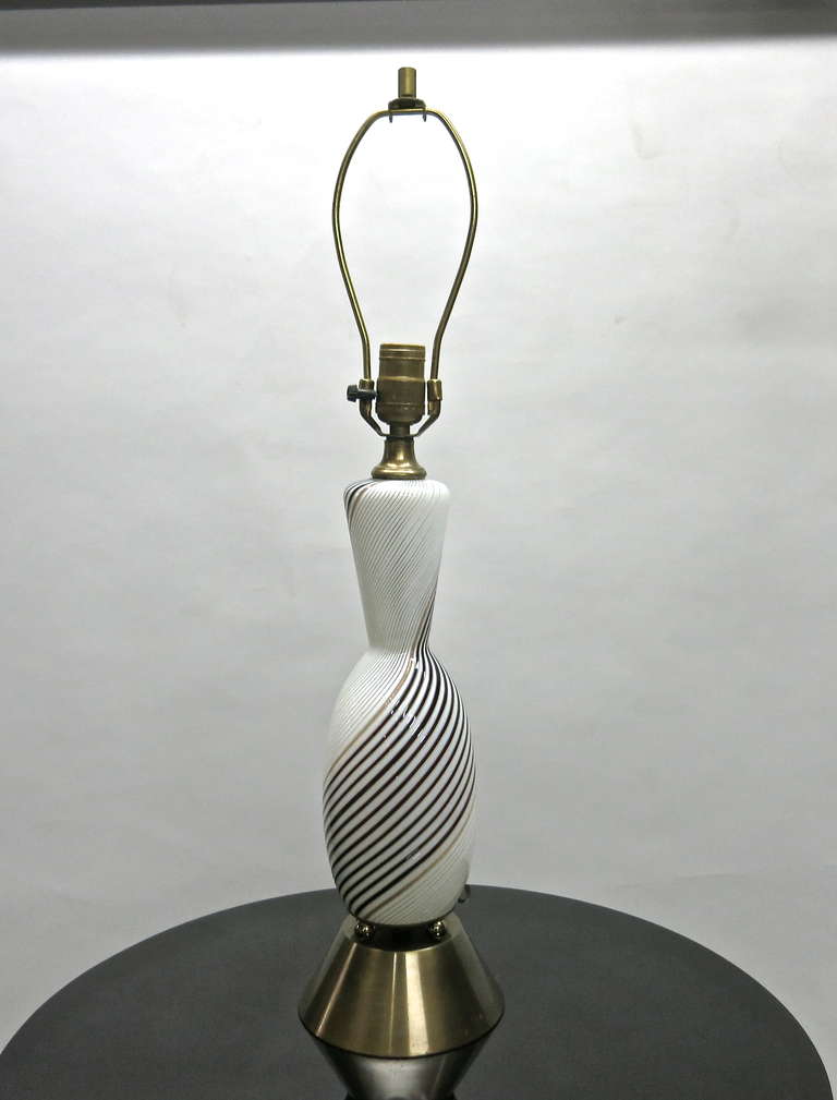 Coppia di lampade da tavolo in vetro rigato mezza filigrana, sfere decorative in ottone tra il corpo in vetro e la base in metallo ottonato patinato.
Le tonalità possono essere ordinate in base alle specifiche.