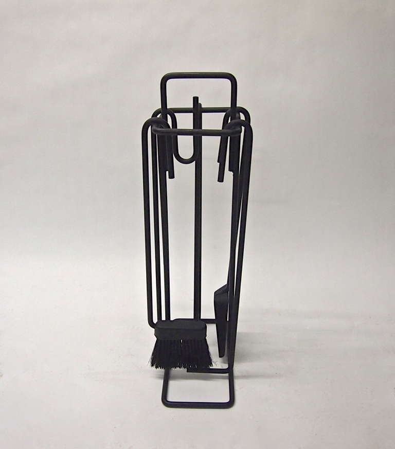 Set of fire tools in black enameled tubular metal includes 5 tools (1 brush, 1 straight poker, 1 L-shaped stoker, 1 spade, and 1 log grabber) and the stand. 
 