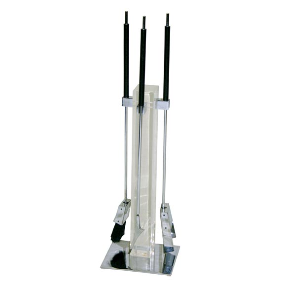 Free-standing fire tool set in chrome-plated steel with a stand that has a clear acrylic block centre and a chrome-plated steel base and hardware. The poker, brush, and spade have black Bakelite/plastic handles.