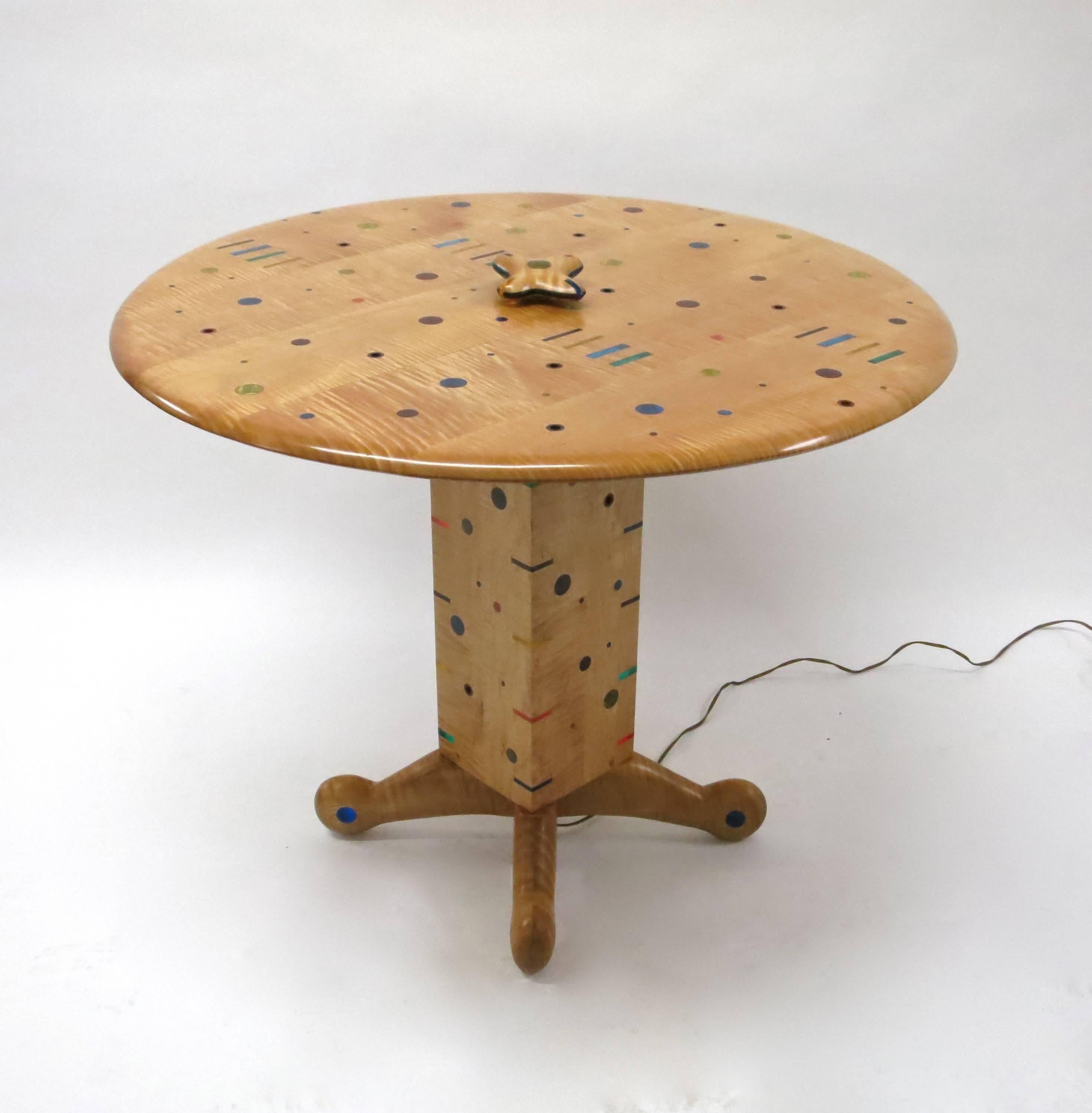 Dining or center table in excellent condition by Daniel Peters commissioned in mid 90's and completed in 1999 for the previous owner.
The table is made of curly maple wood with colored acrylic accents in shapes of full circles, hollow circles, and