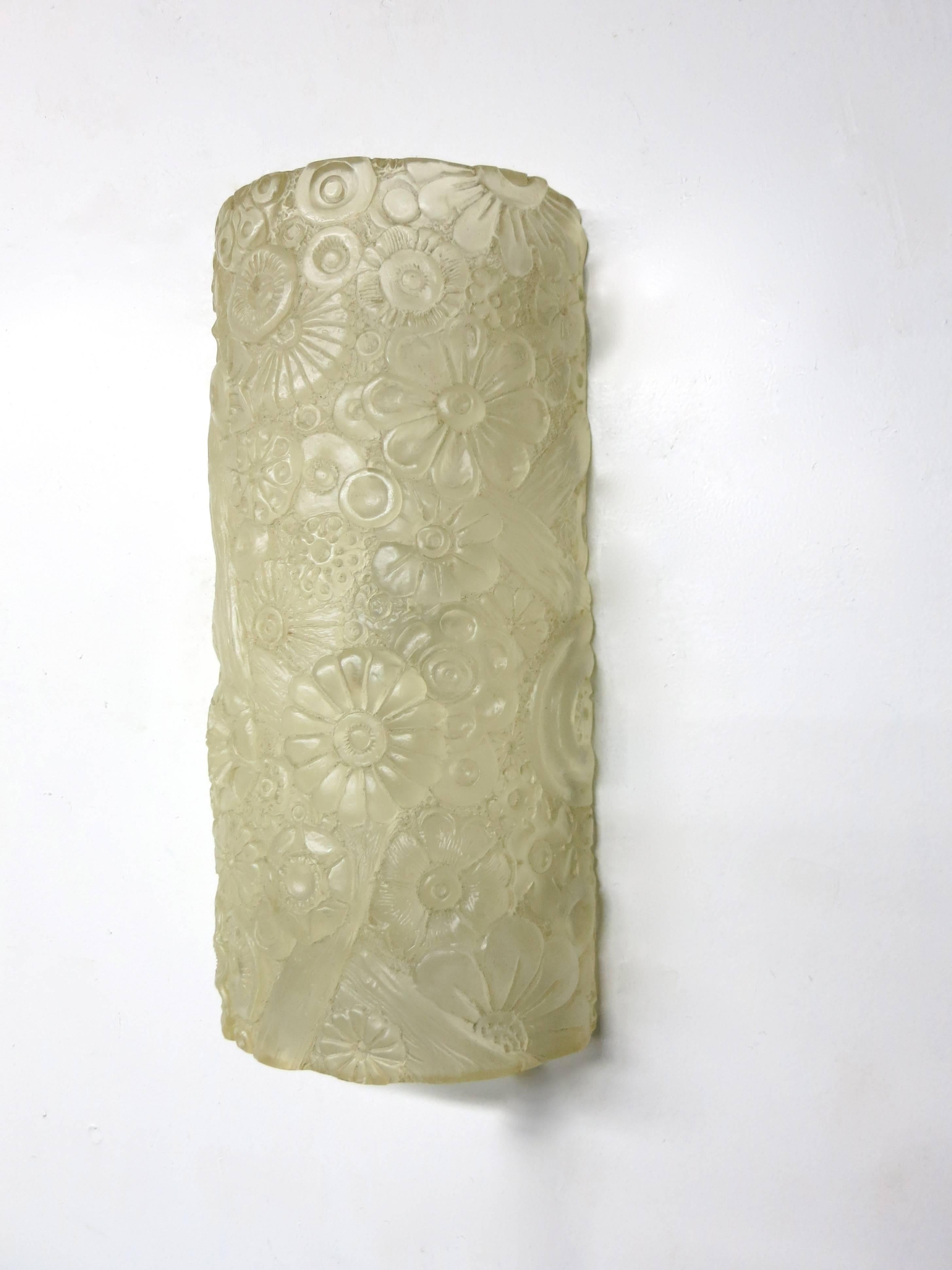Wall sconce with a half round cast resin shade that flush mounts. The floral detail shade hides two standard American sockets and a mounting plate.
