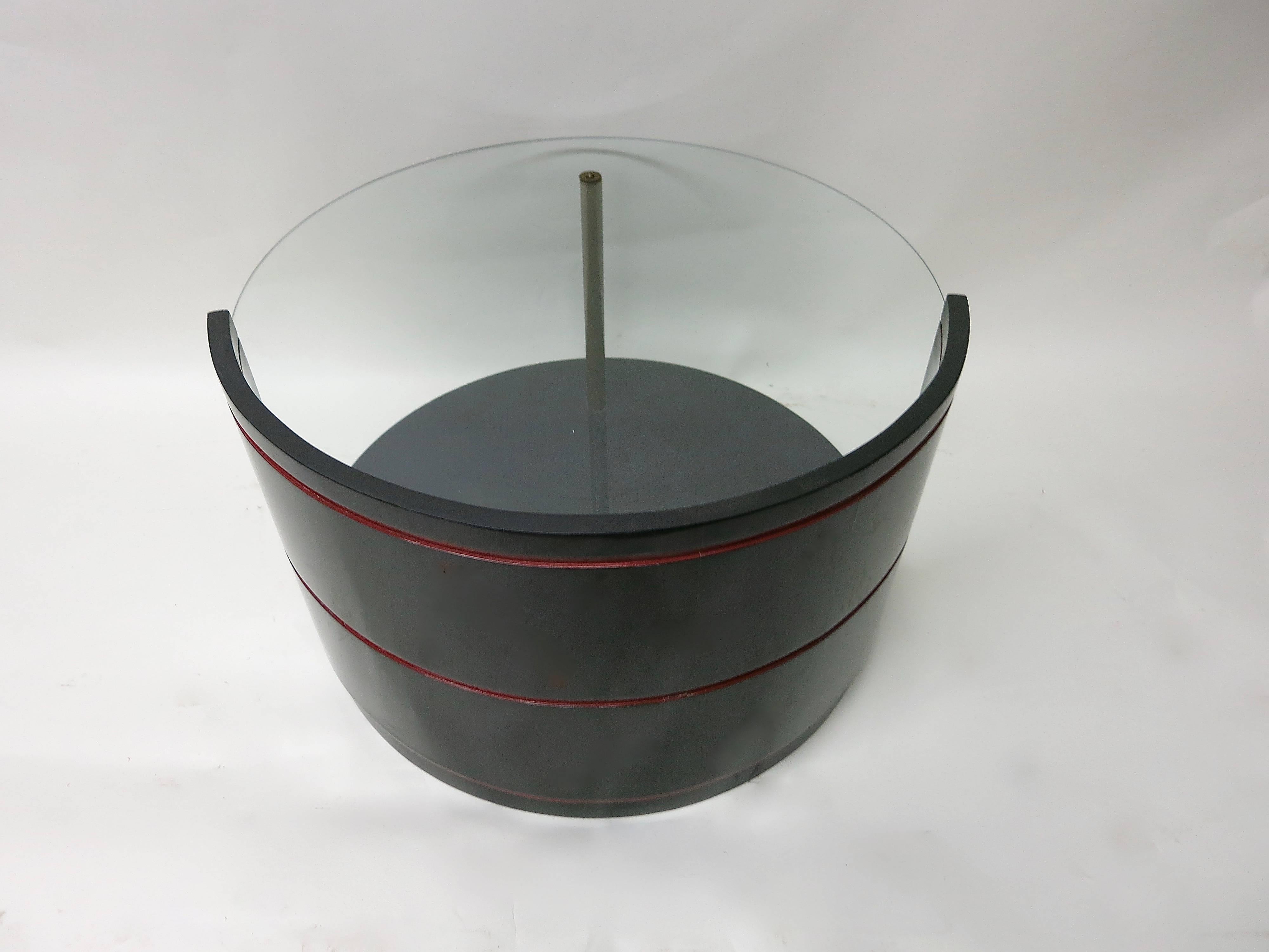 Restored cocktail or side table in black and red lacquer over wood with a round glass top and a patinated brass tube. 