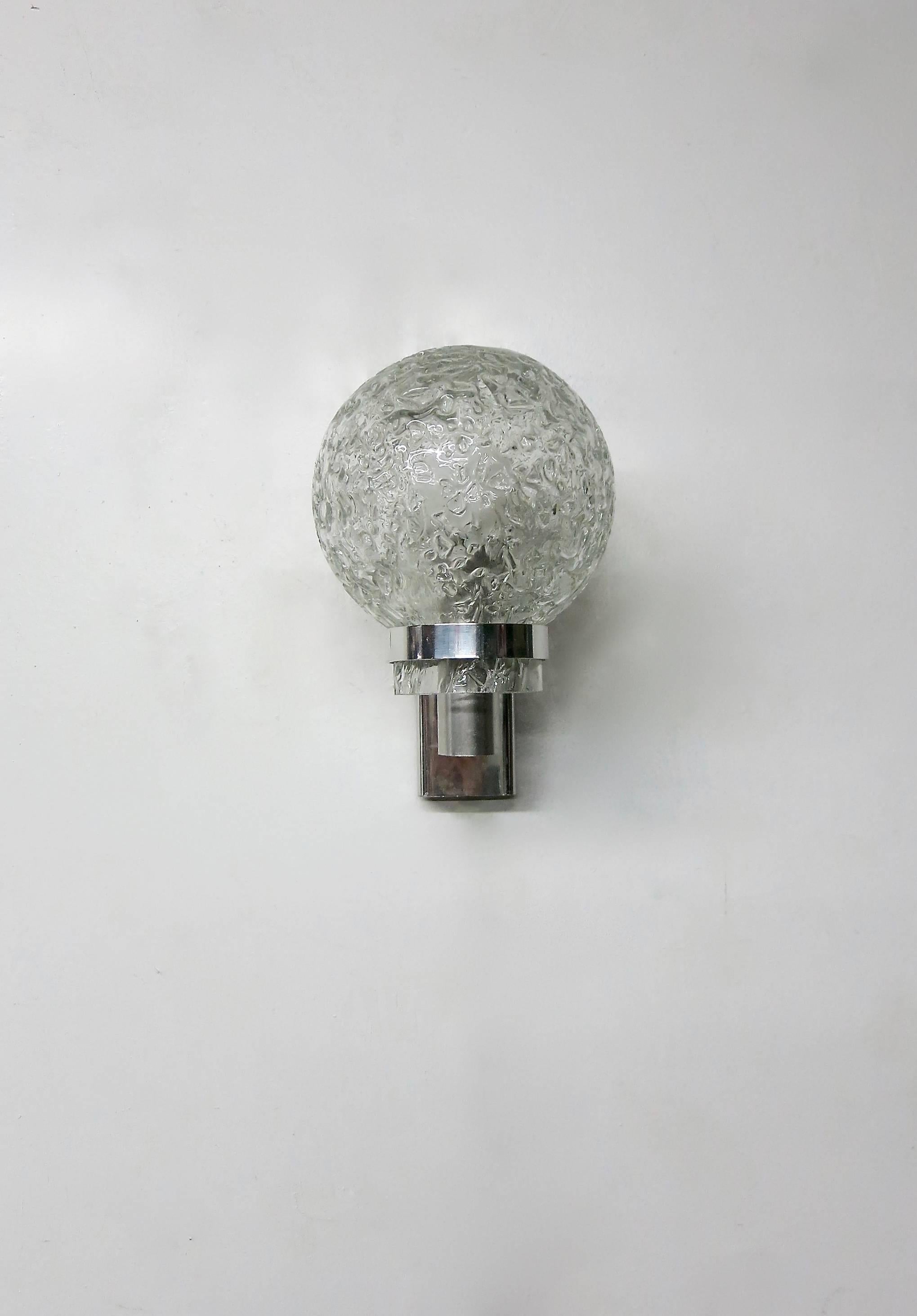 Italian mid-century modern chrome sconces. Each sconce has a single arm supporting a round textured glass shade covering a single socket. The wiring has been changed to an American candelabra socket if desired, the sconces can be changed to an