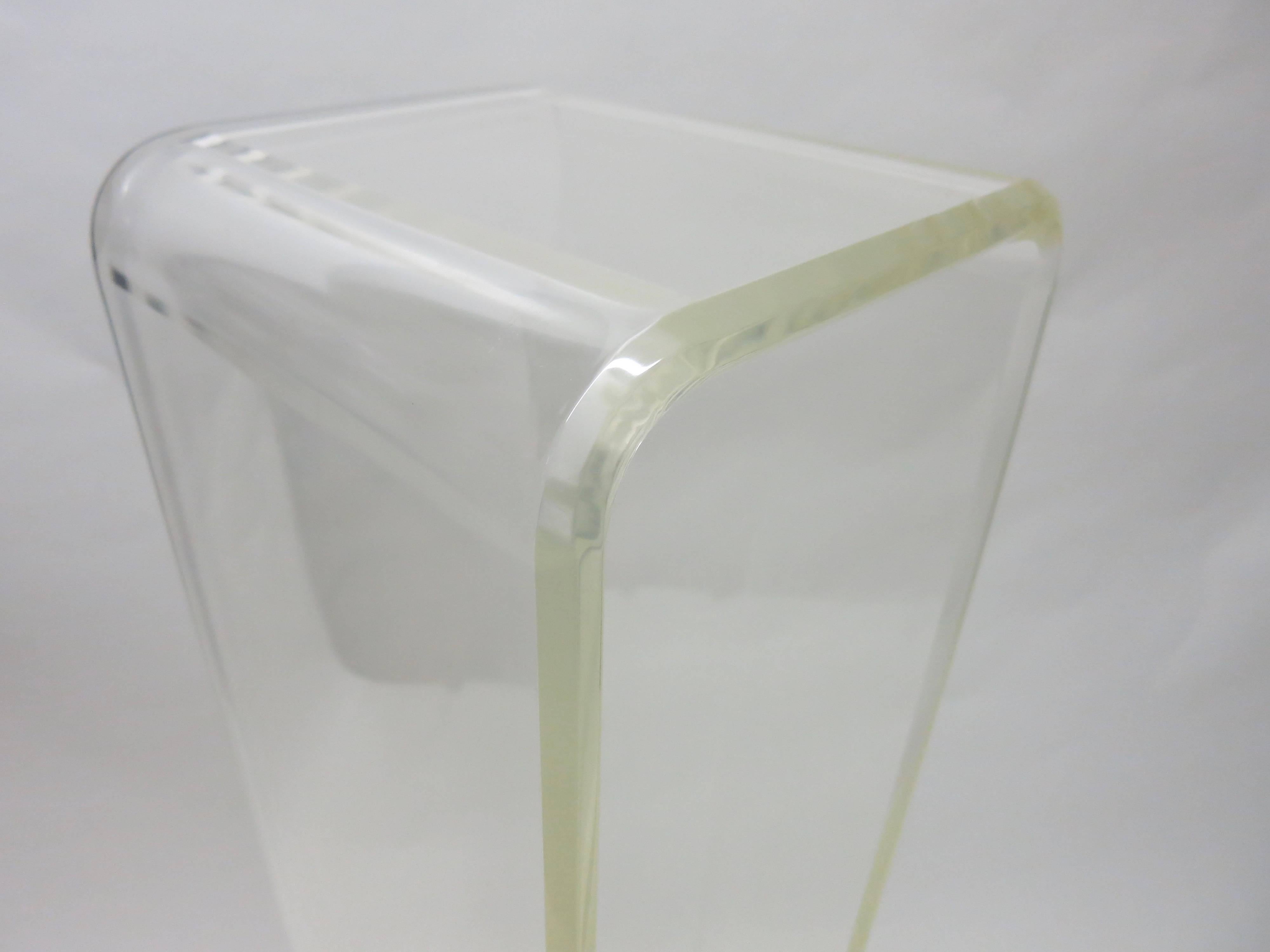 Pedestal made of clear molded Lucite. The flat top is square with rounded ends. The bottom has rounded ends that turn outward to give the pedestal good balance combined with the weight of 3/4 inch thick Lucite make for a stable and strong stance.