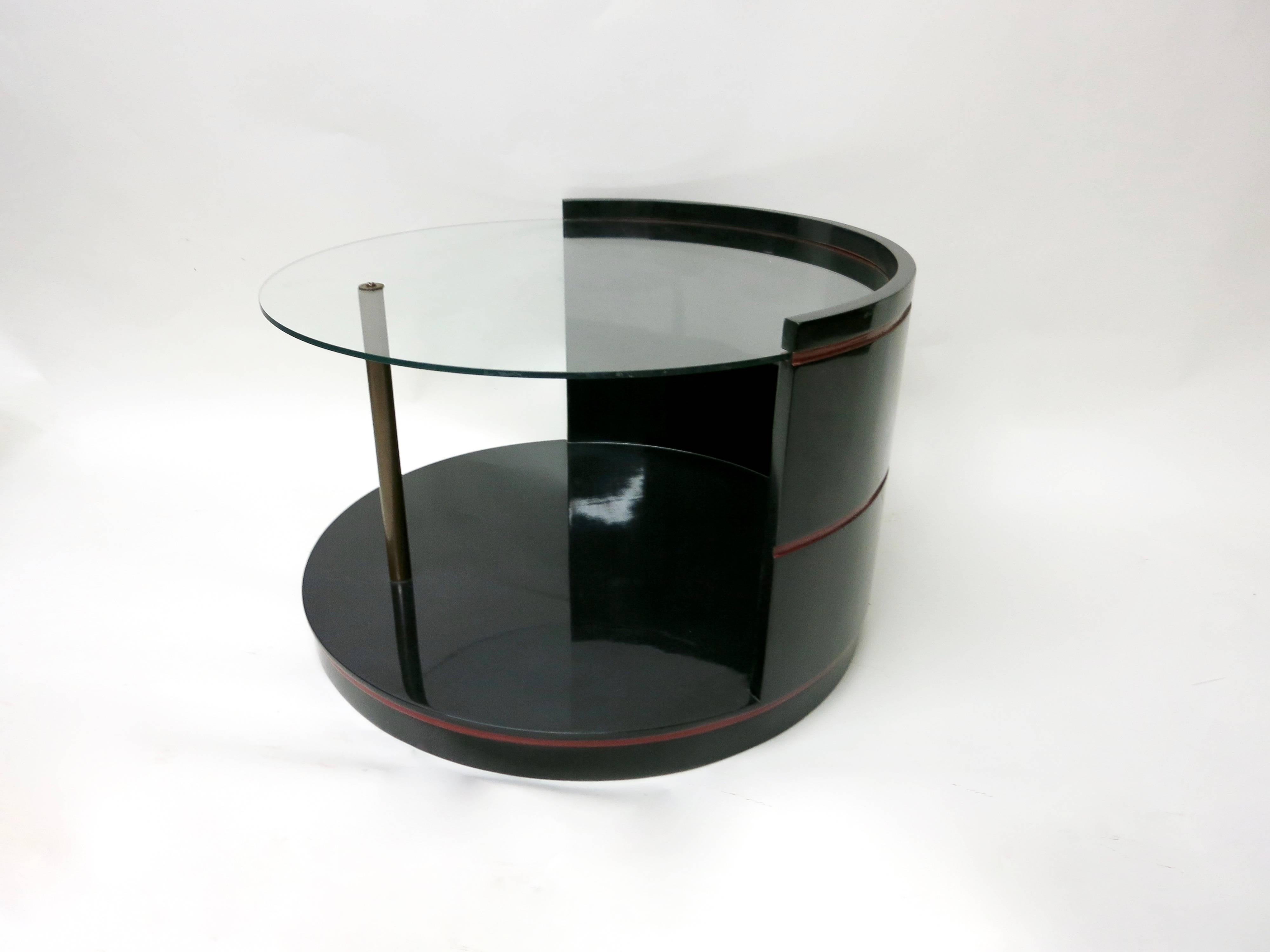 A side table and a cocktail table both finished in black with red detail lacquer.
Side table has three levels with the top glass with patinated brass supports between each level. The round cocktail table has a glass top also supported by a