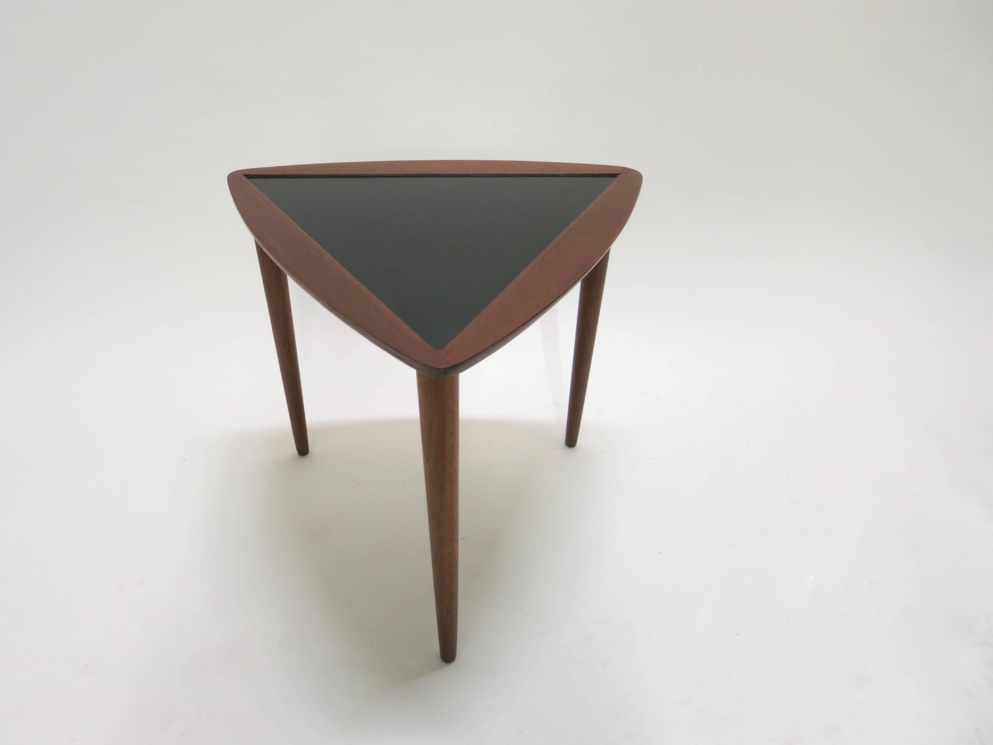 Three triangular stacking tables have an inset black laminate top framed in walnut each with three tapered spindle legs also in walnut. Sturdy strong tables in excellent condition.