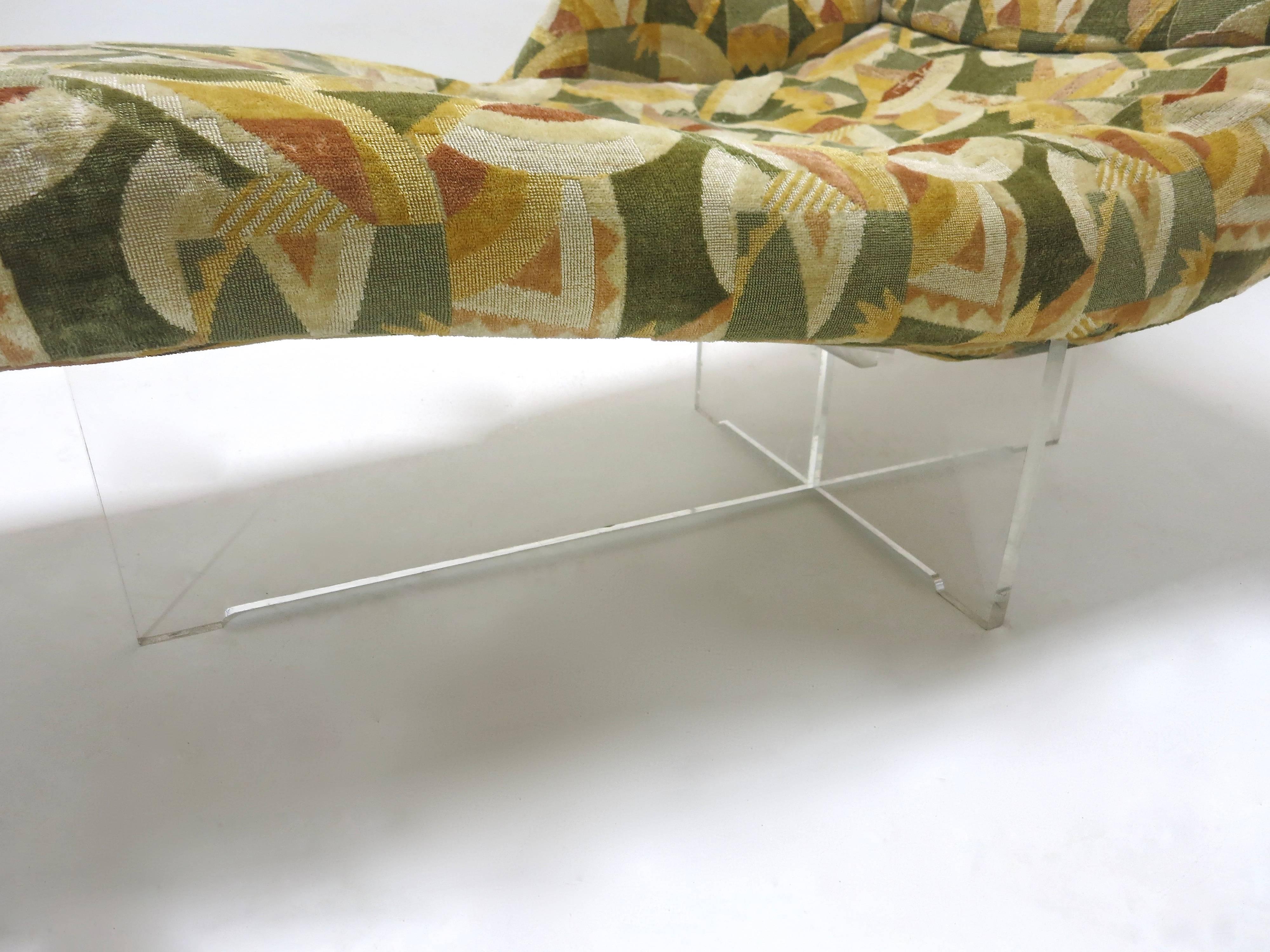 Chaise longue in original condition. A Vladimir Kagan designed in 1969. The chaise has an arm on the rights side with a Lucite base that criss crosses under the seat. The sofa has been kept in near perfect condition with the original fabric.
